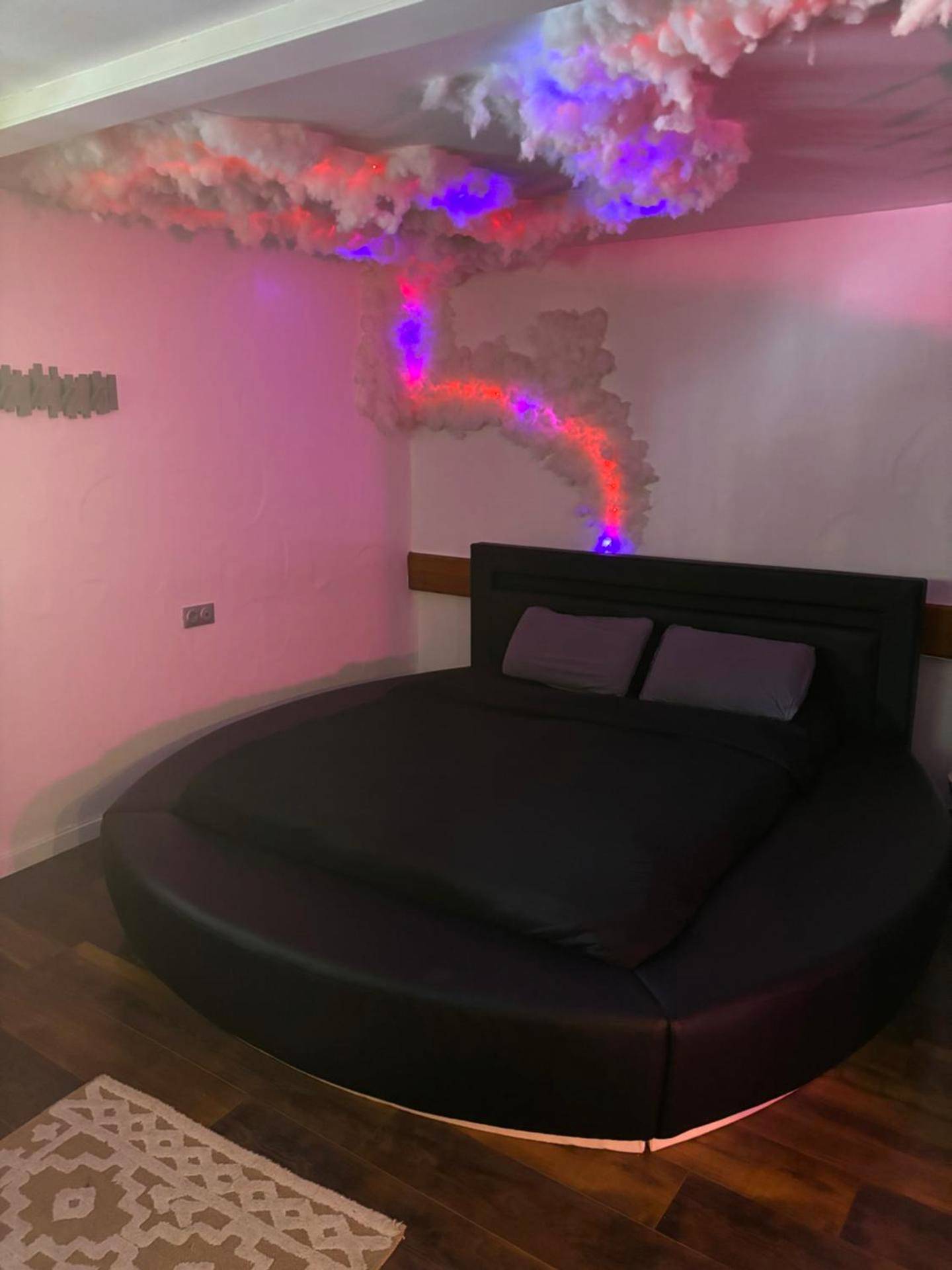 Lit rond noir sous un plafond de nuages lumineux - Le 36/Espace bien - être privatif