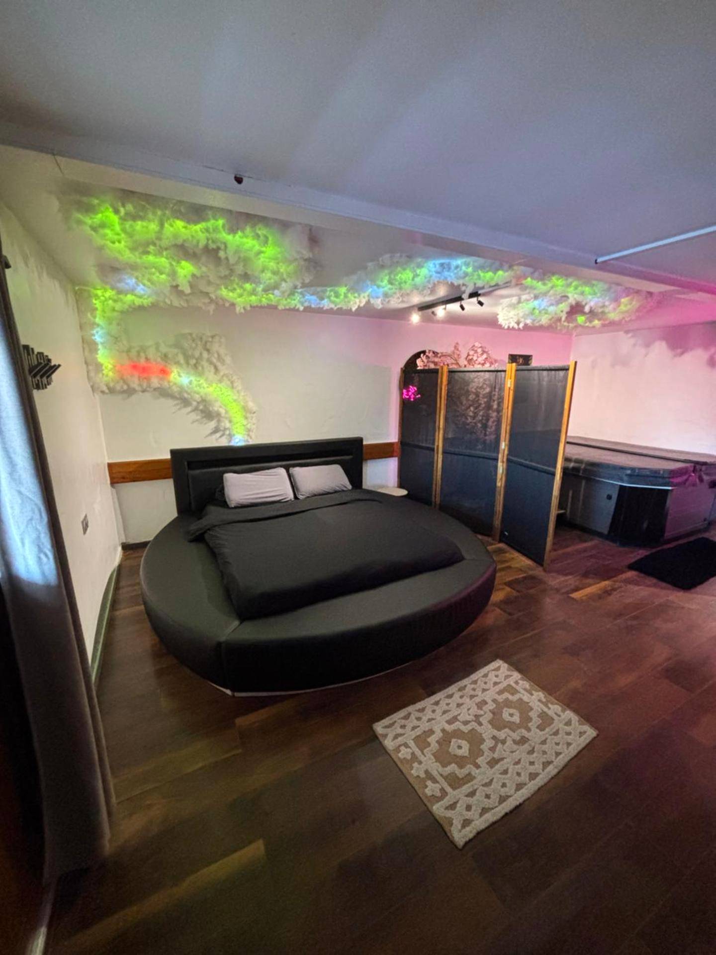 Chambre avec lit rond et jacuzzi en arrière - plan - Le 36/Espace bien - être privatif