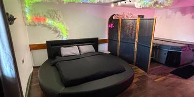Chambre avec lit rond et jacuzzi en arrière - plan - Le 36/Espace bien - être privatif