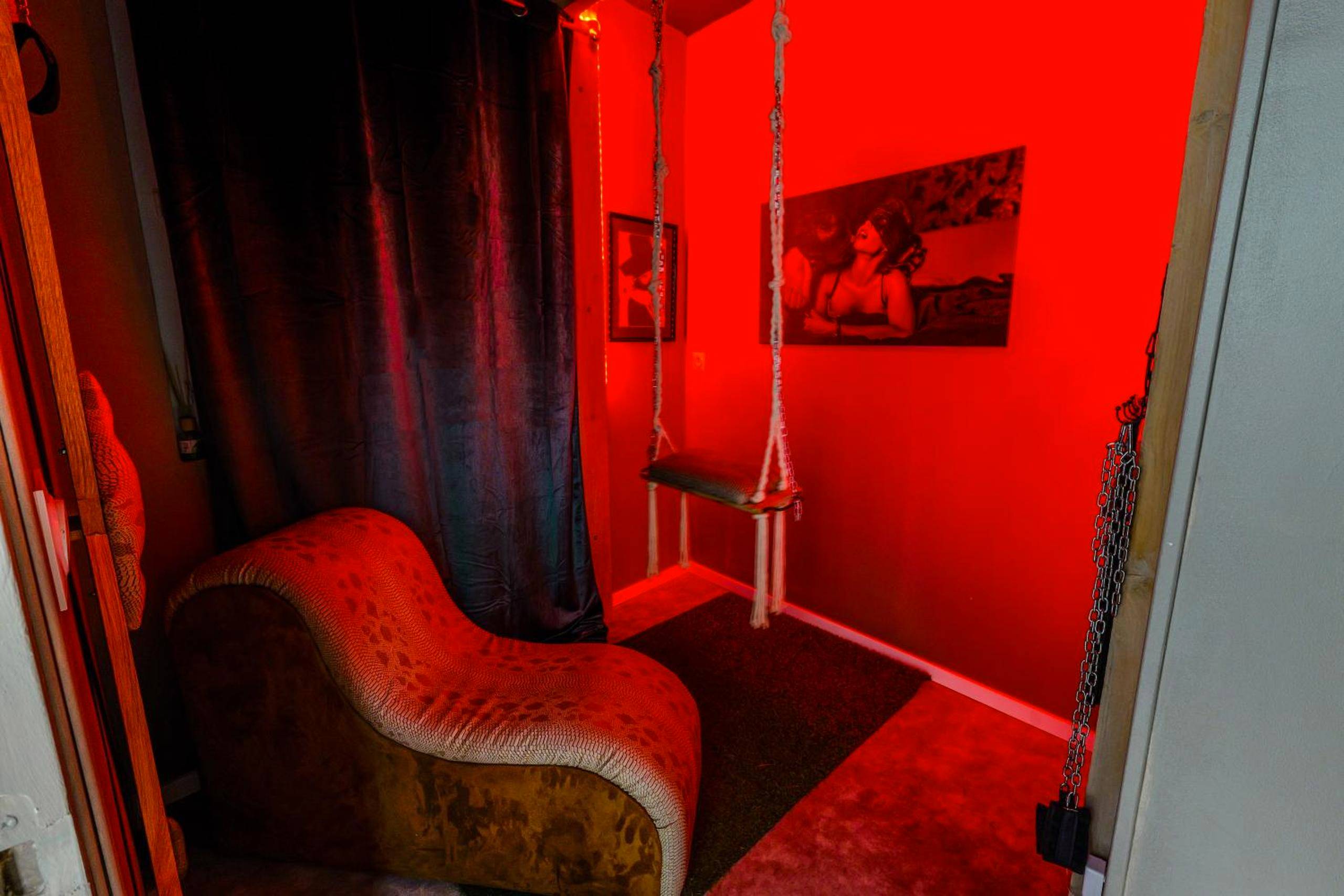 Fauteuil tantrique et balançoire sous lumière rouge - Love Room Rouen - 50 Nuances Nirvana - Love Room à Rouen