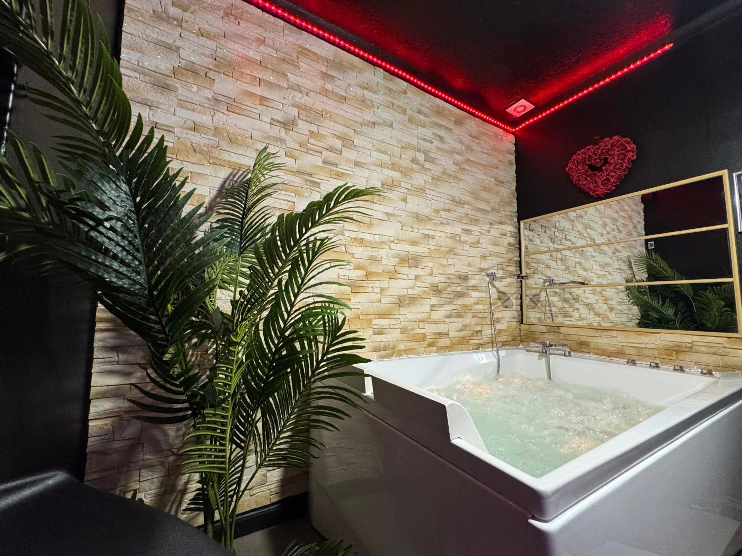Baignoire balnéo devant un mur en pierre - LOVE ROOM Adulte Only