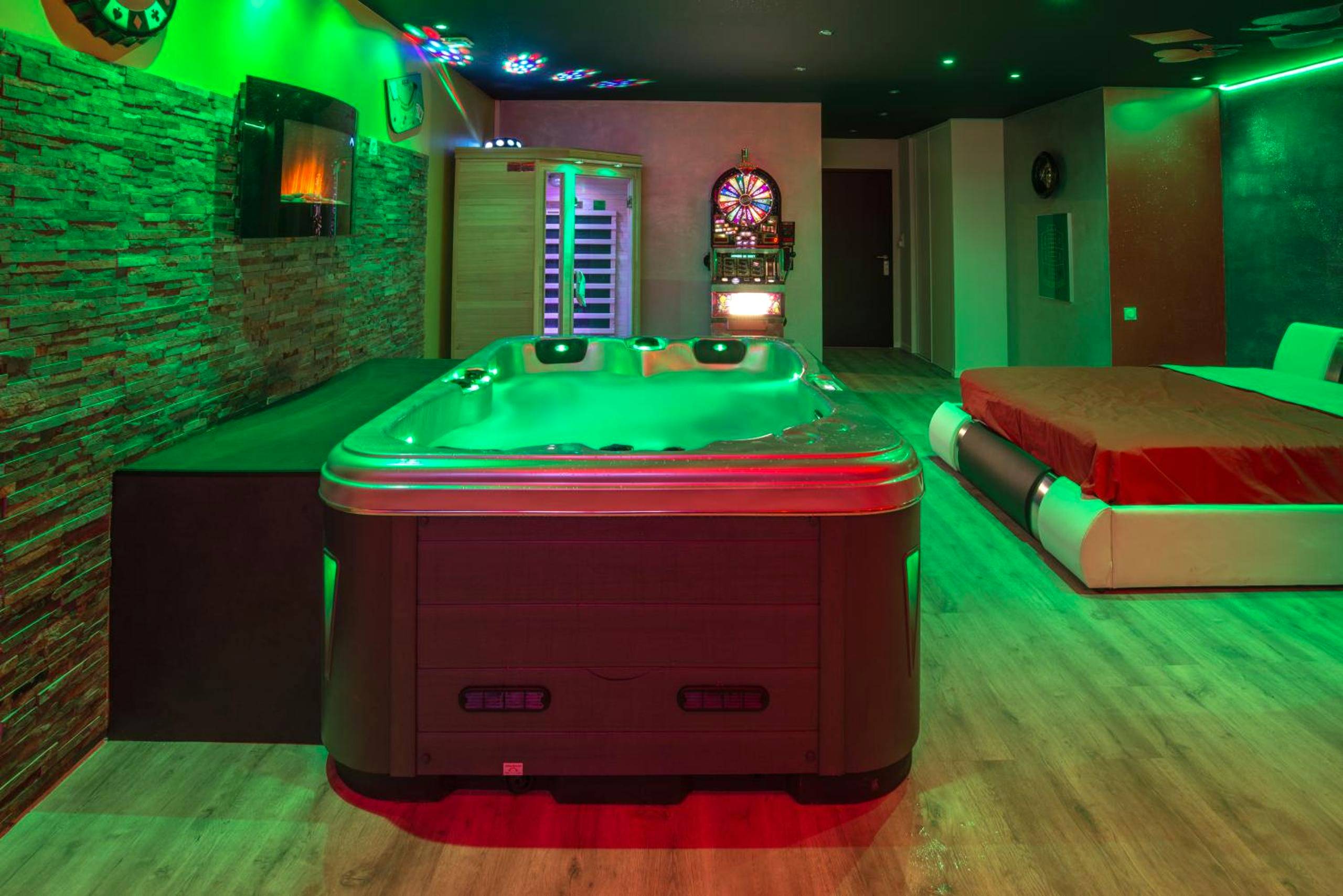 Jacuzzi central, sauna et lit avec néons verts - American spa motel
