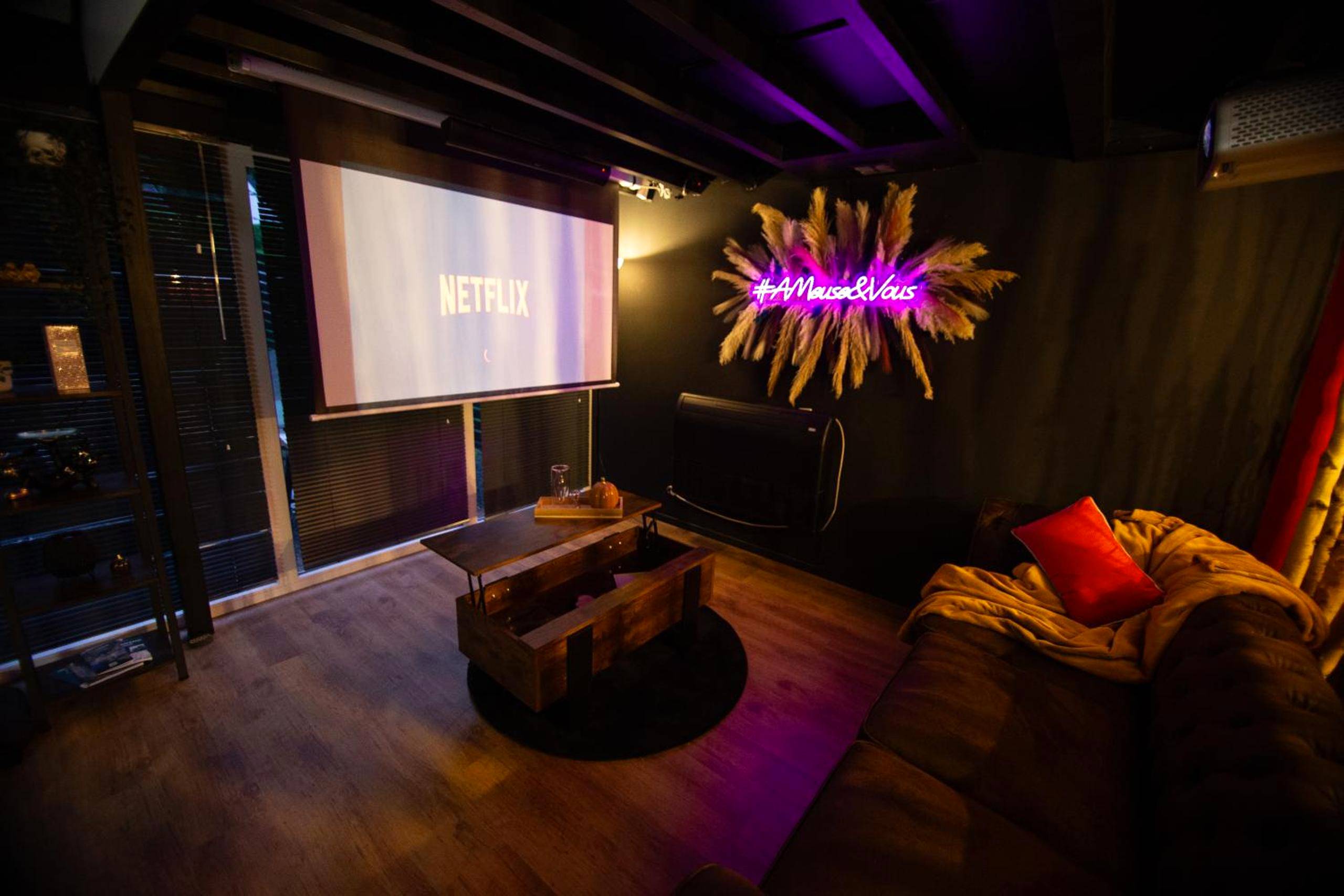 Salon cinéma avec écran géant et canapé - Love Room AMeuse&Vous