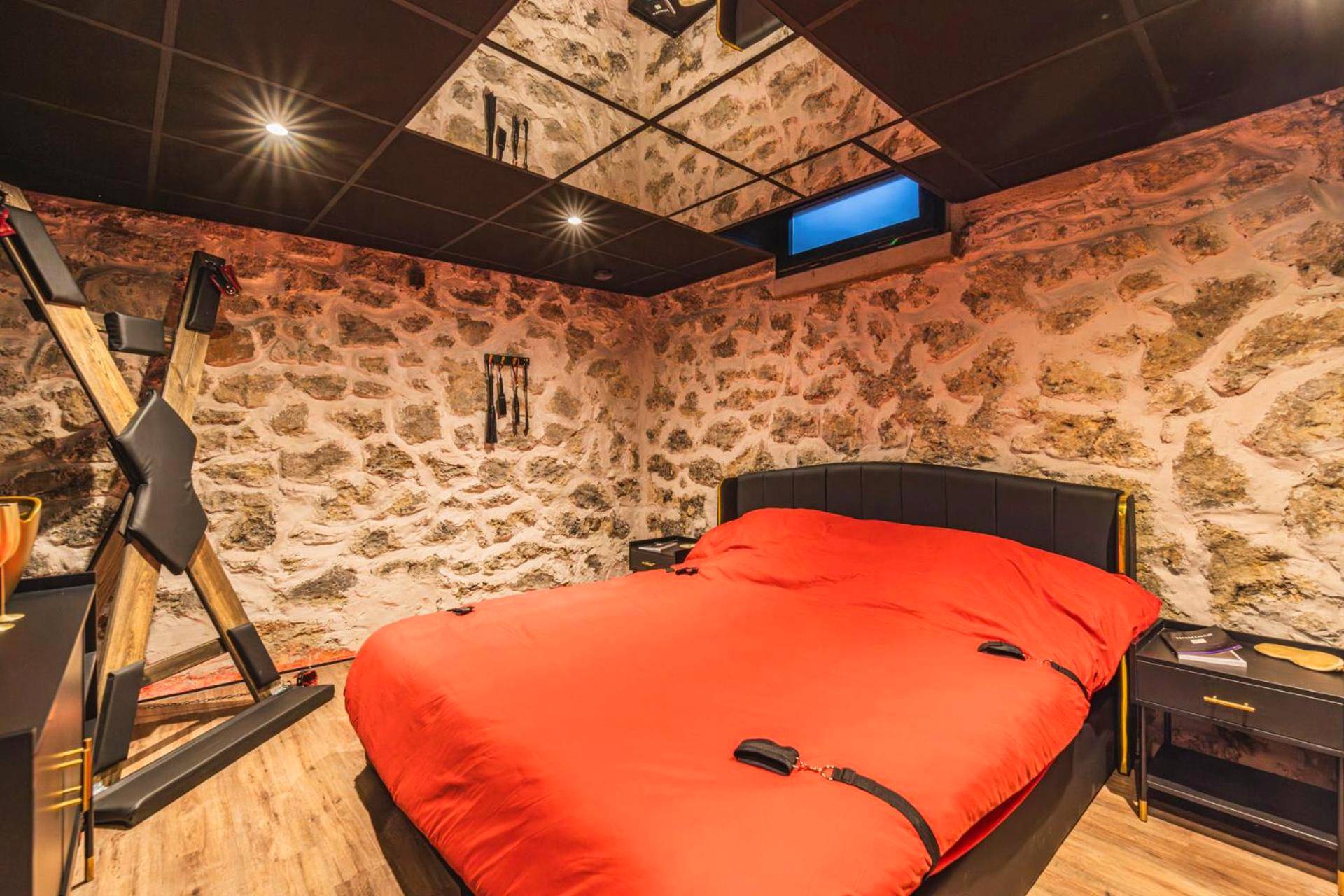 Lit king size rouge devant un mur en pierre - Amsterdam