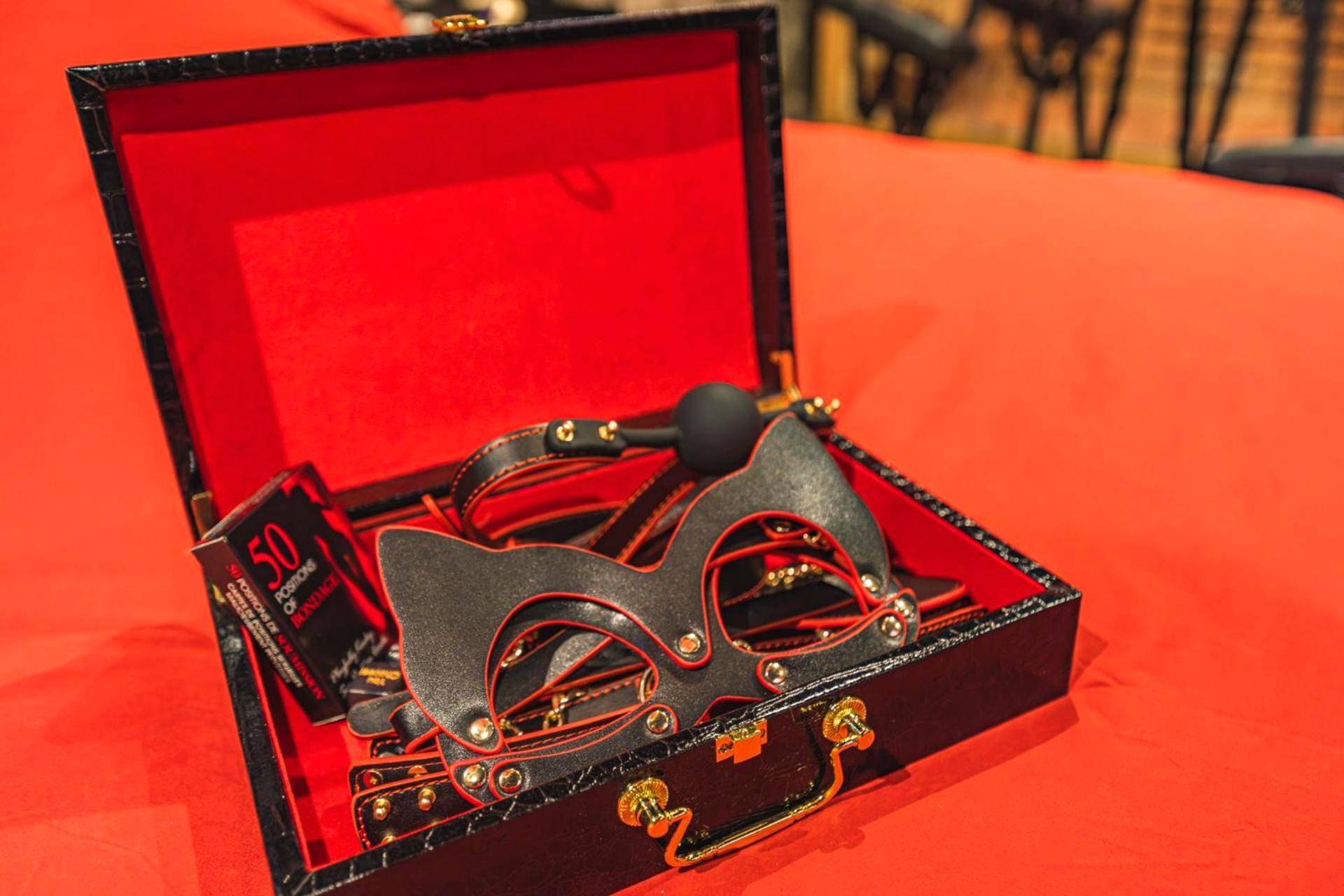 Coffret d'accessoires érotiques sur lit rouge - Amsterdam