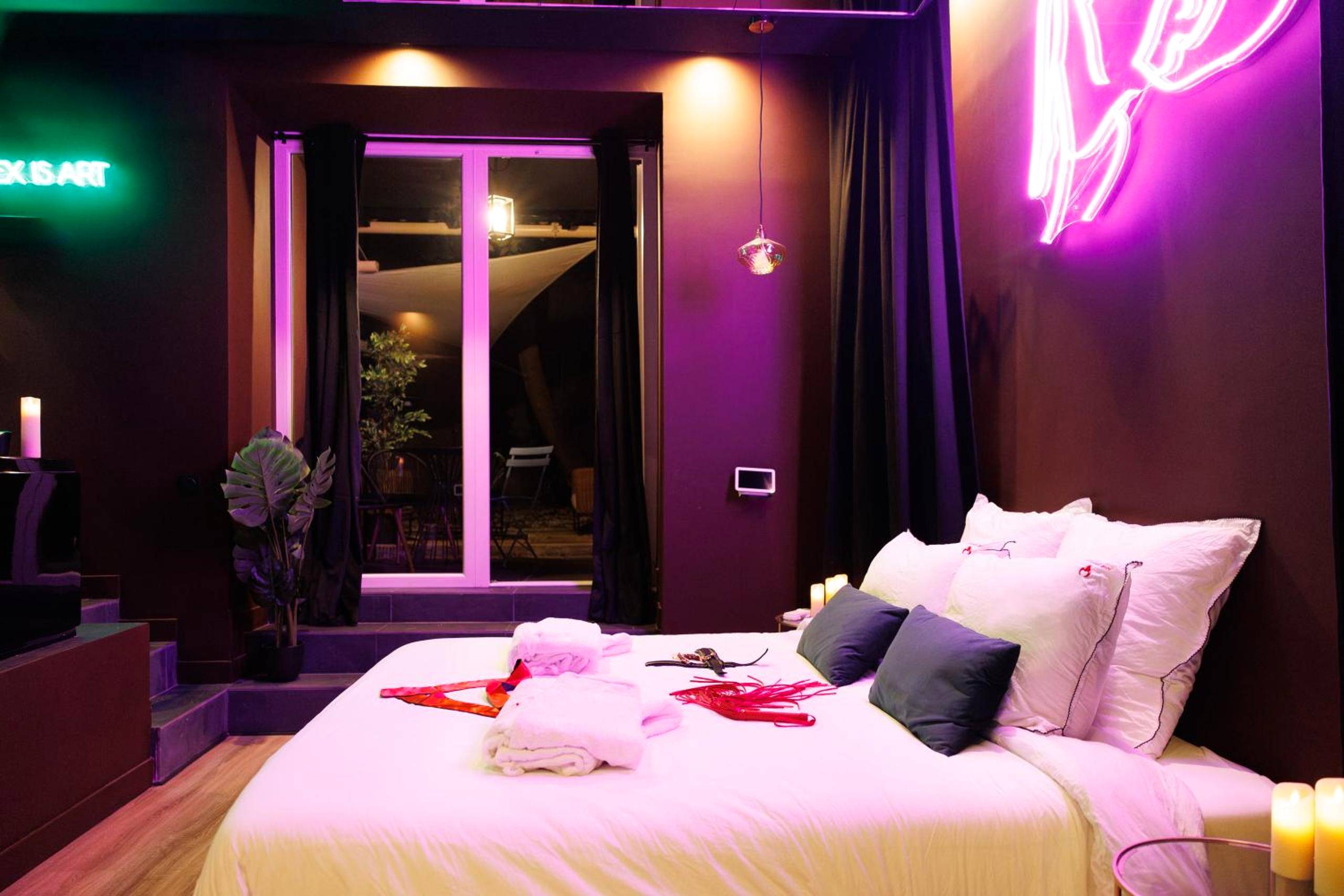 Lit double et accessoires sous néon rose - Love Room Marseille - Aphrodisia