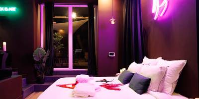 Lit double et accessoires sous néon rose - Love Room Marseille - Aphrodisia