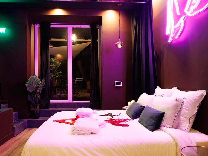 Lit double et accessoires sous néon rose - Love Room Marseille - Aphrodisia