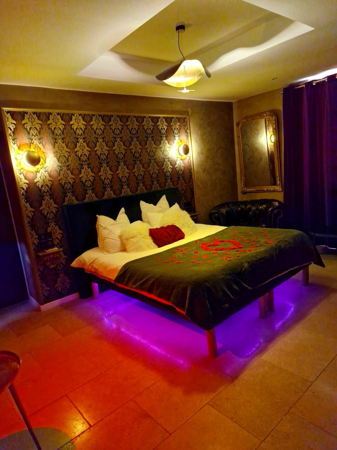 Lit king size avec pétales et néons violets - Love Room Saint - Zacharie - L'Aphrodite Jacuzzi privatif