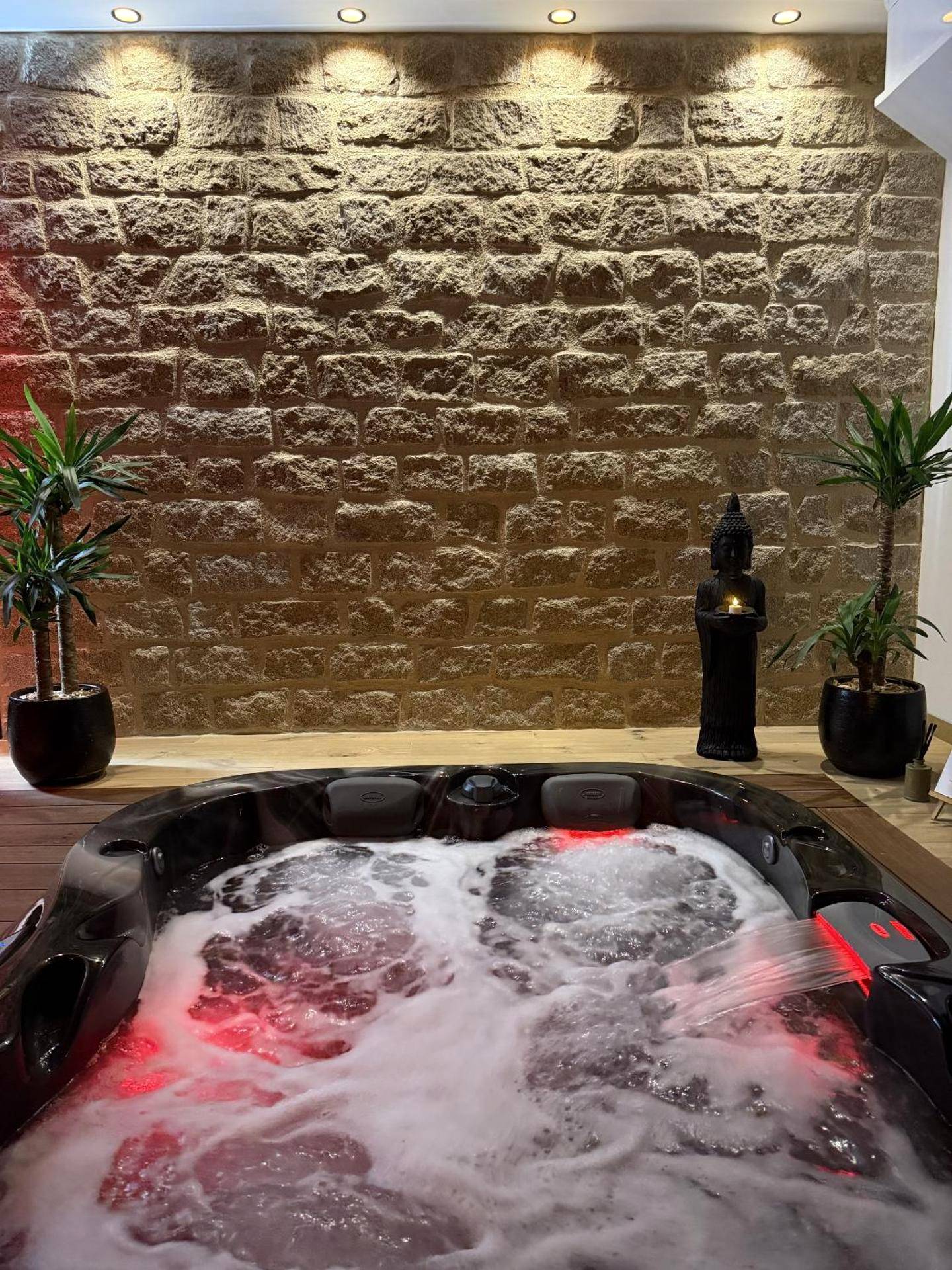 Jacuzzi bouillonnant devant un mur en pierre - L'Apogée
