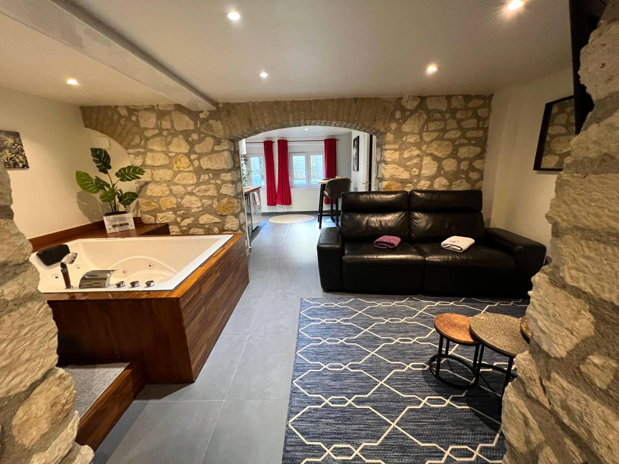Jacuzzi rectangulaire et canapé dans salon voûté - Appart Spa Privatif