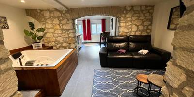 Jacuzzi rectangulaire et canapé dans salon voûté - Appart Spa Privatif