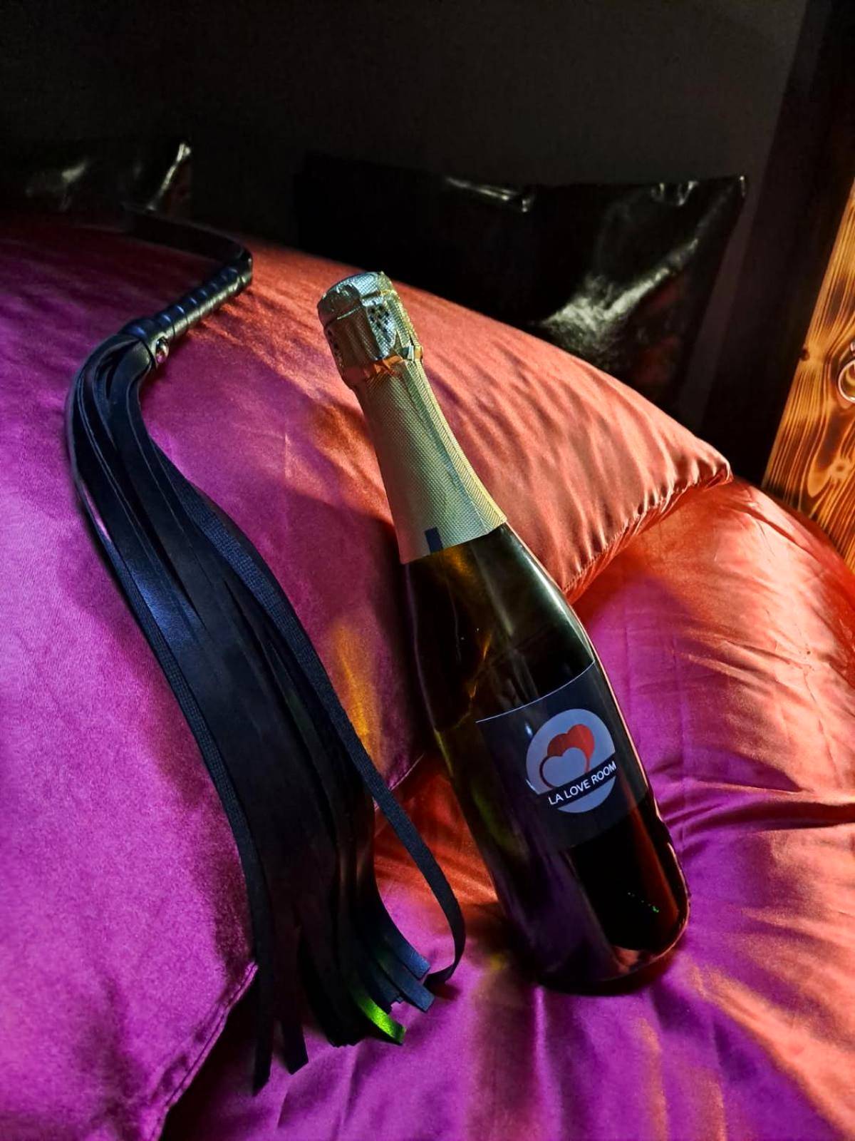 Bouteille de champagne et fouet sur lit de soie - Love Room Arbois - La Love room