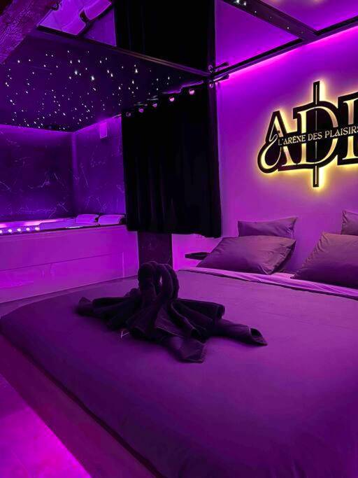 Lit king size et jacuzzi sous néons violets - L’arène des plaisirs - love room