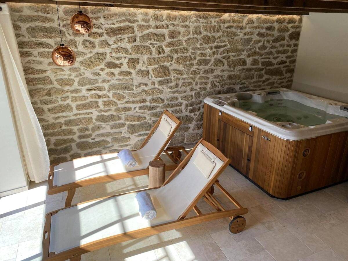 Transats en bois face au jacuzzi et mur en pierre - L'Arôme