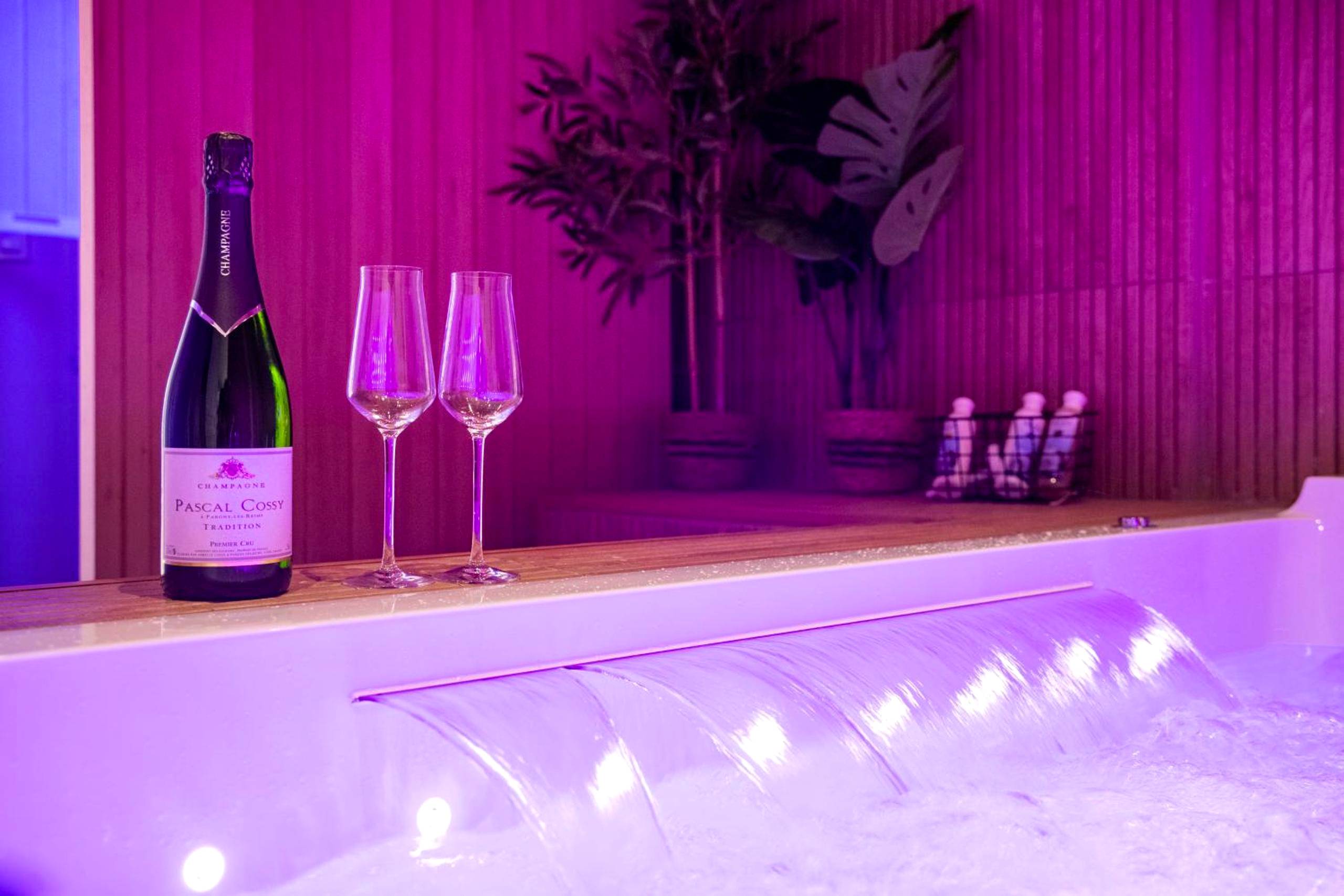 Détail du jacuzzi éclairé en rose avec flûtes - Art Déco Champagne & Spa