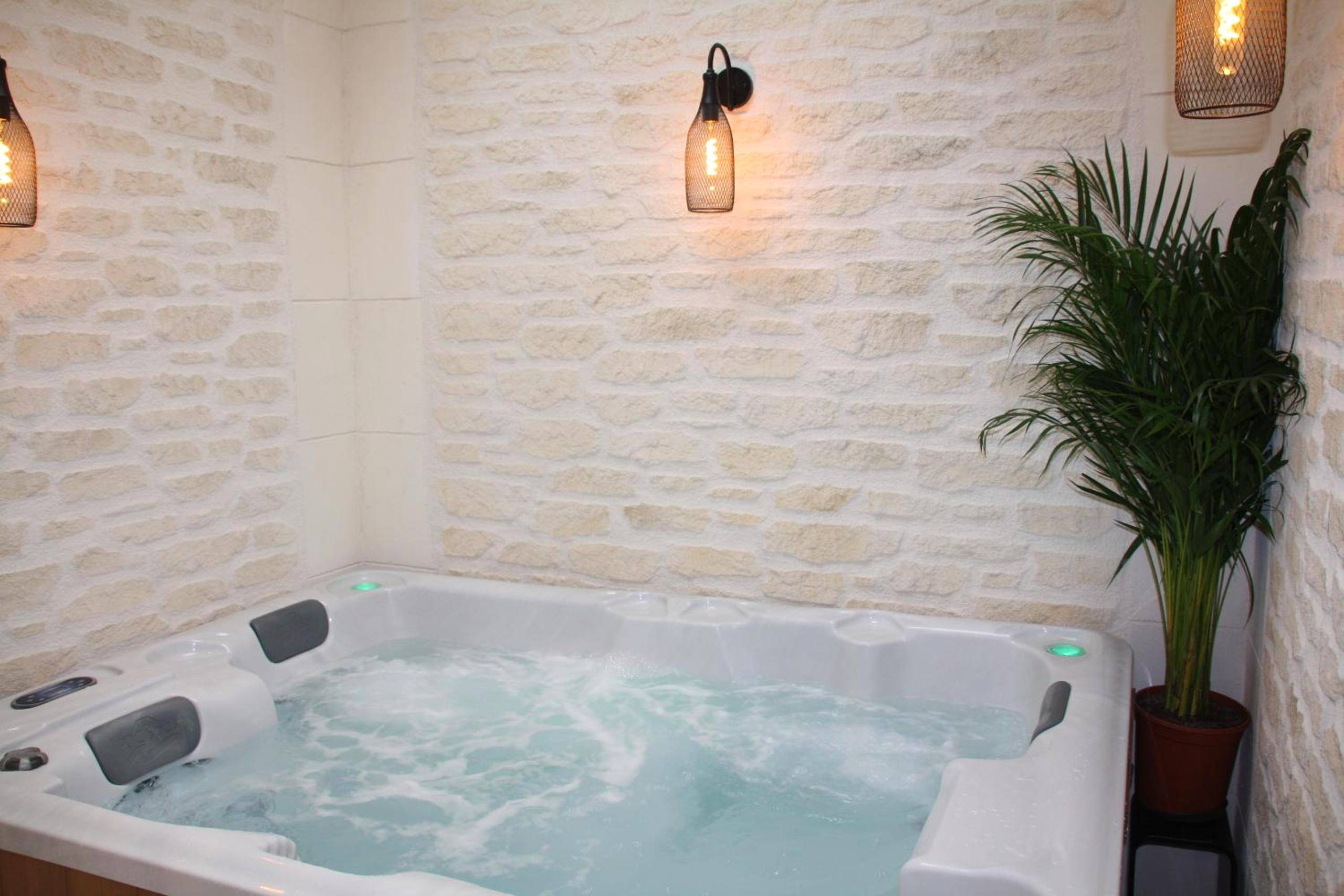 Bain à remous et mur en pierres apparentes - L'Atelier - Gîte & Spa