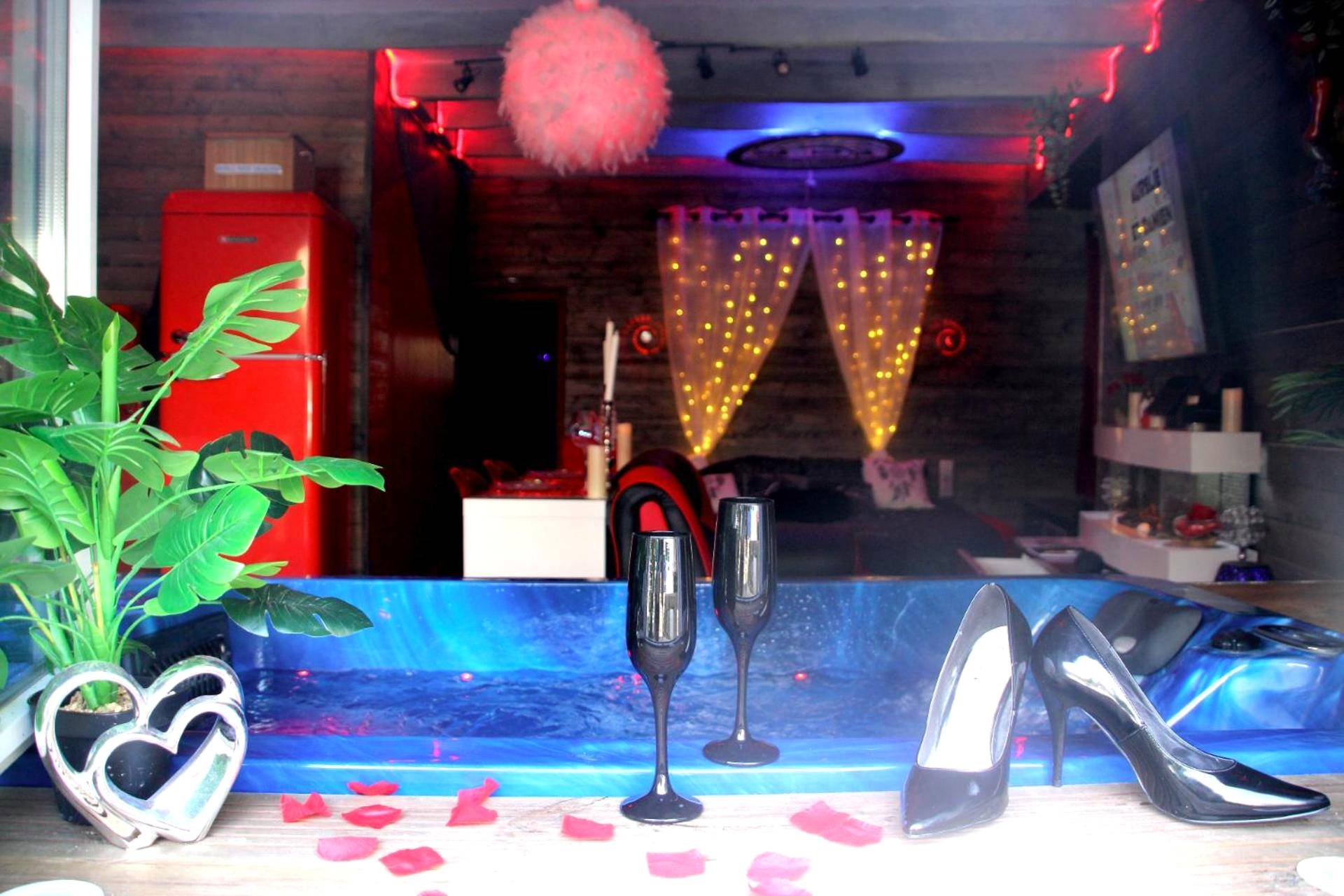 Jacuzzi bleu avec flûtes et pétales de rose - Love Room Caden - L'Attrape Rêves - Gîte Le Romantique