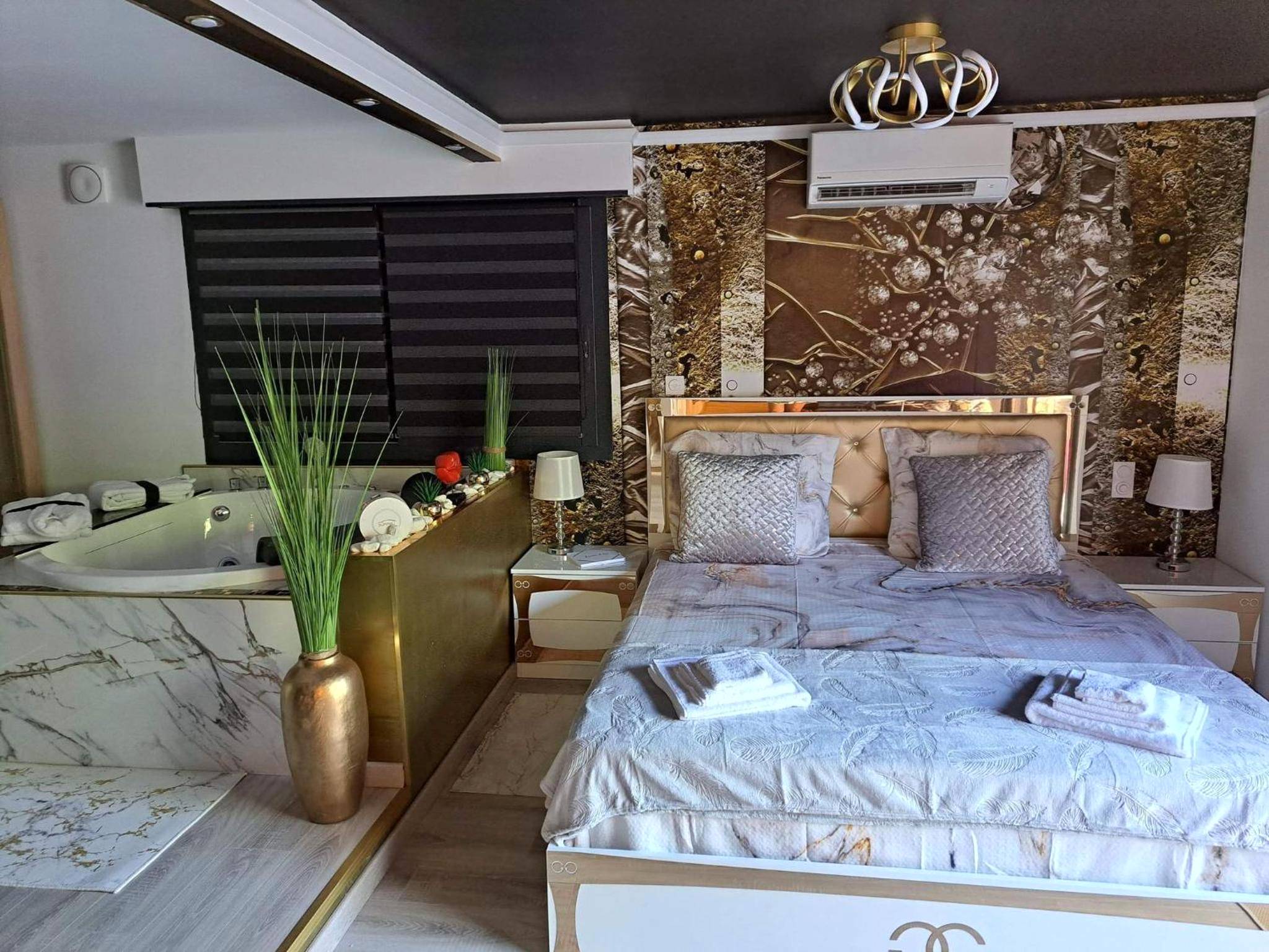 Lit double et baignoire balnéo marbrée - L'Aurore Love Room de prestige jacuzzi sauna piscine chauffée cuisine