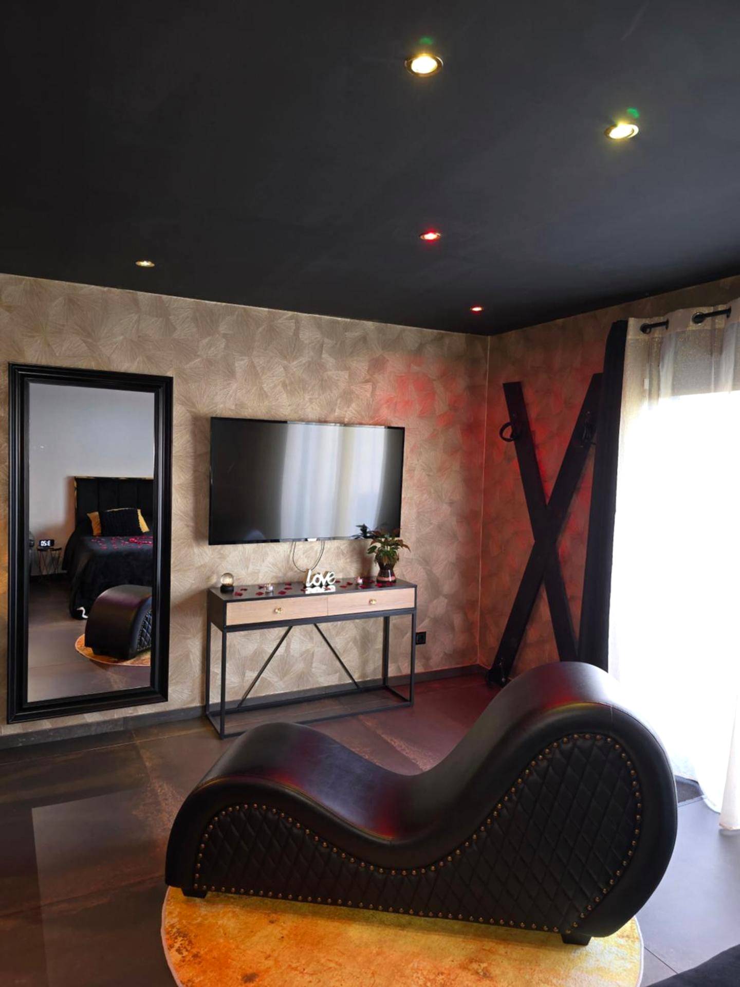 Fauteuil tantrique, croix de Saint - André et TV - Avec toi suite spa La Secrète