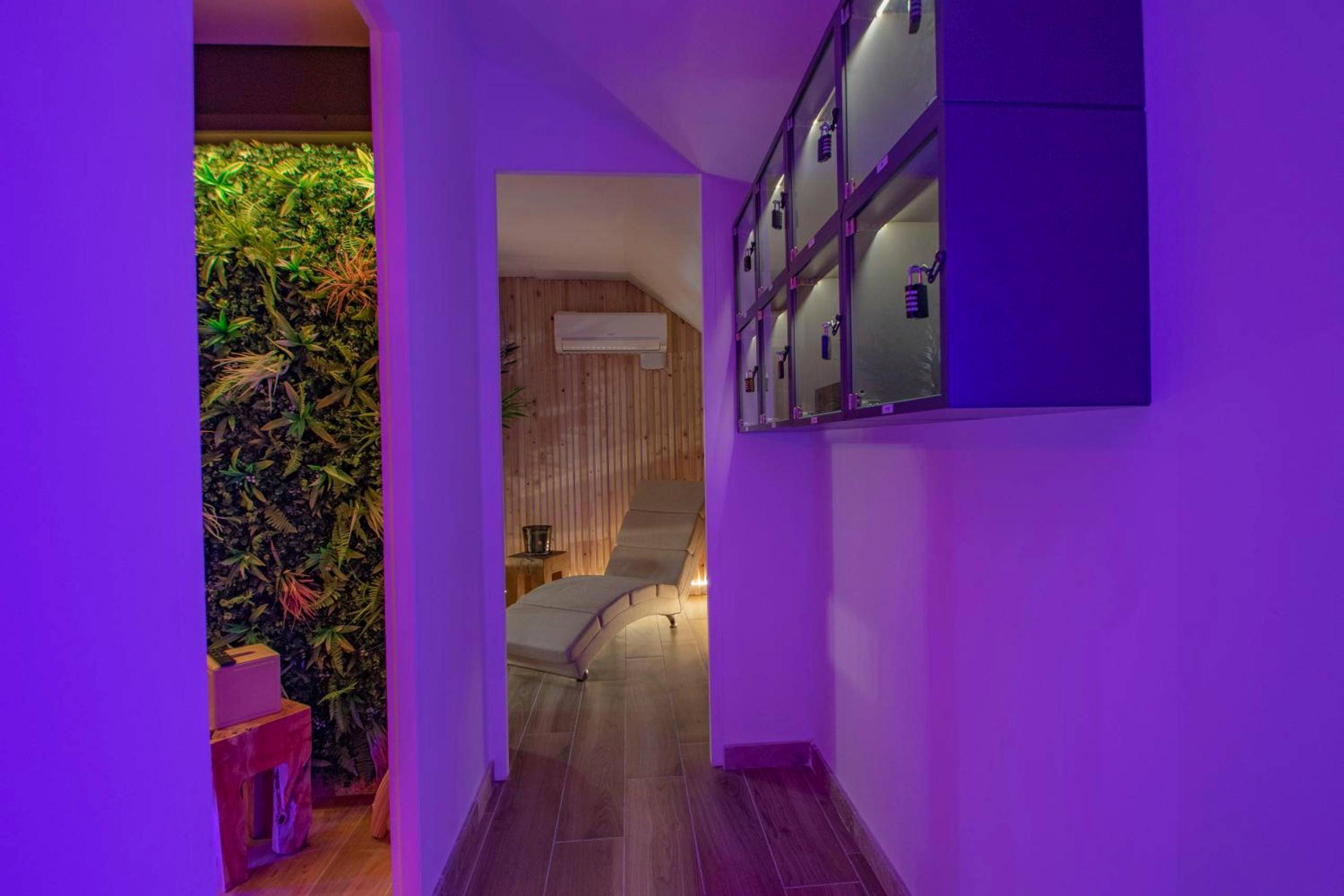 Couloir avec mur végétal et éclairage violet - LES BAINS D’EROS