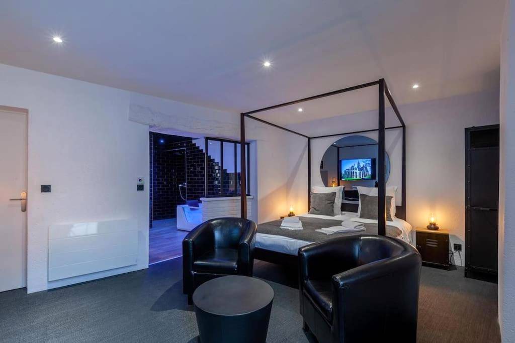 Lit à baldaquin et fauteuils en cuir noir - Love Room Bayeux - Bayeuzen - Le Baldaquin - Nuitée avec Spa Privatif
