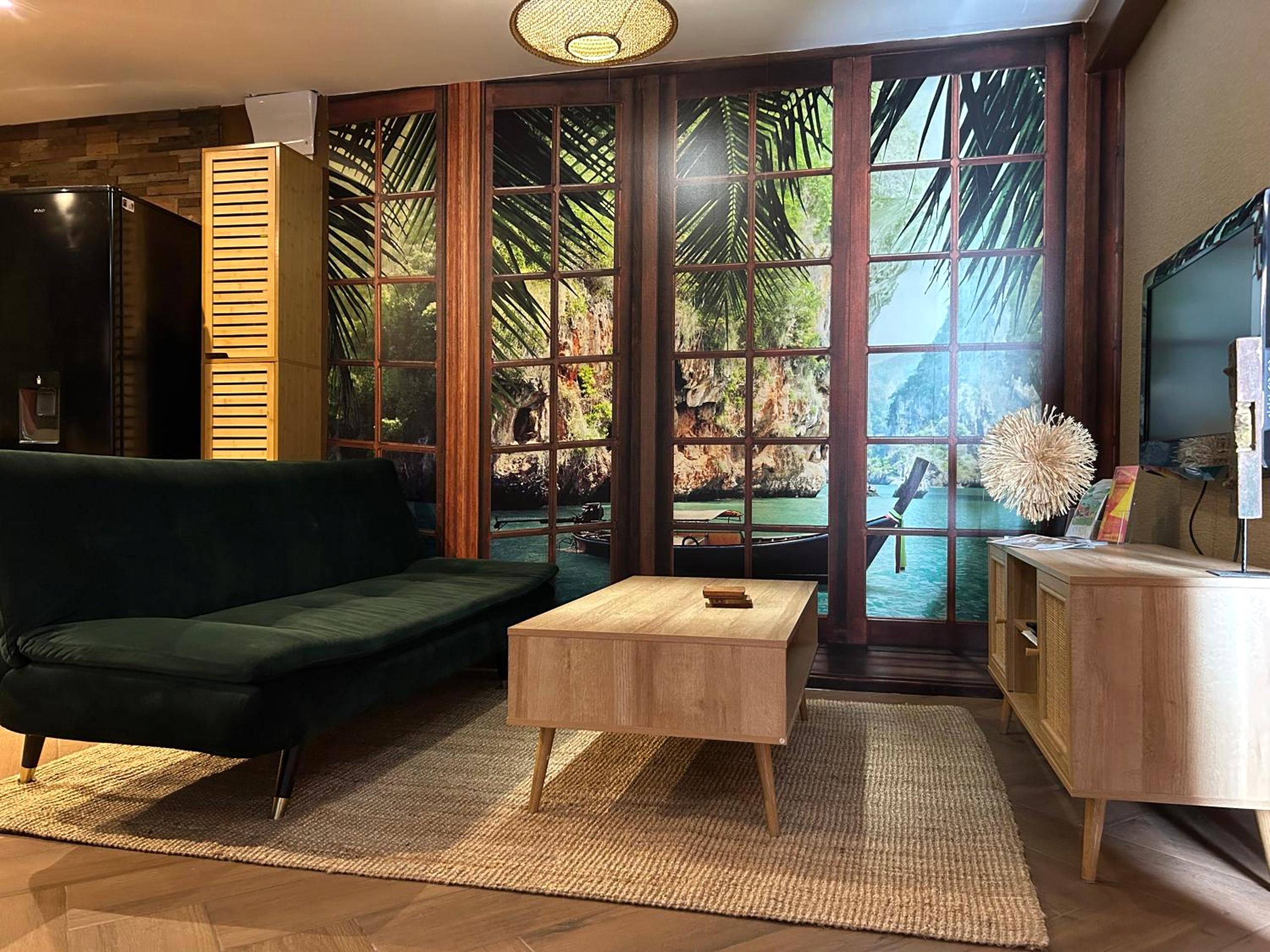 Salon avec canapé vert et fresque tropicale - La Balinaise, a Normandy getaway