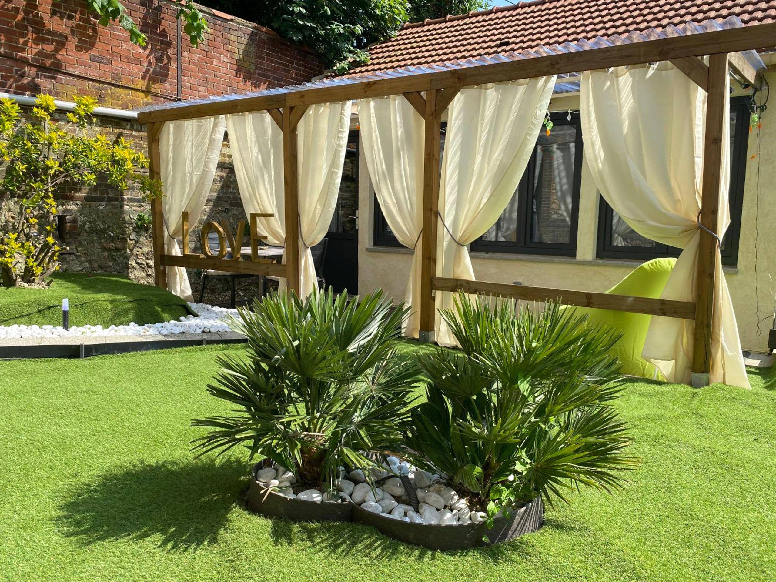 Terrasse aménagée avec rideaux et gazon - Balnéo, sauna et de nombreuses surprises