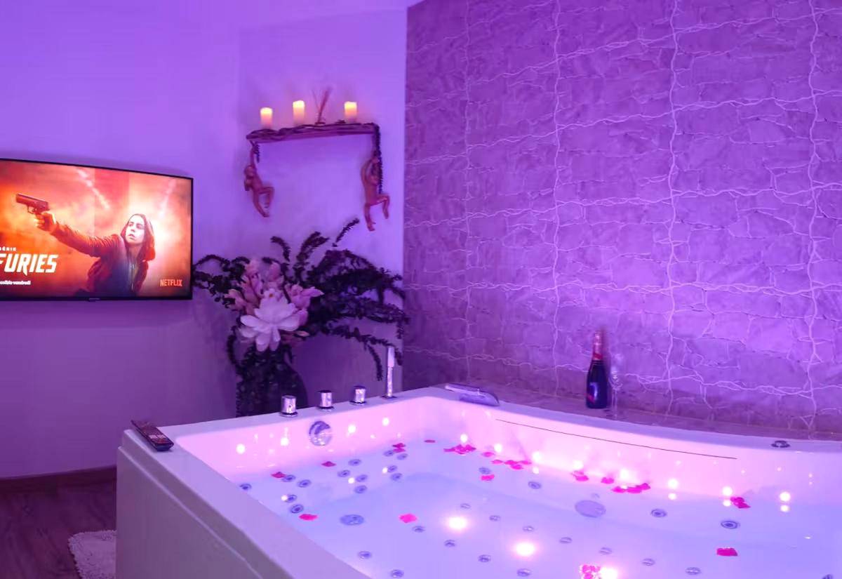Jacuzzi privatif avec éclairage tamisé violet - Love room balnéo sauna Le Havre