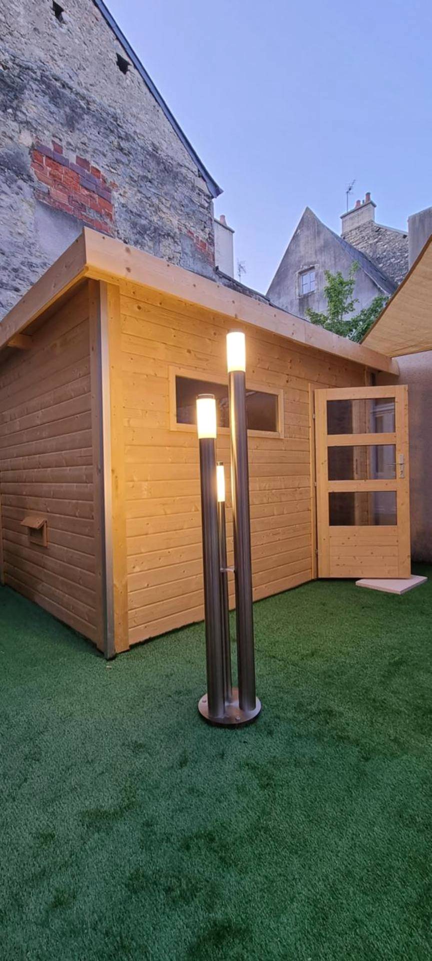 Chalet en bois sur gazon synthétique avec lampe - Bayeuzen Le Jardin - Nuit Romantique et Spa Privatif Bayeux