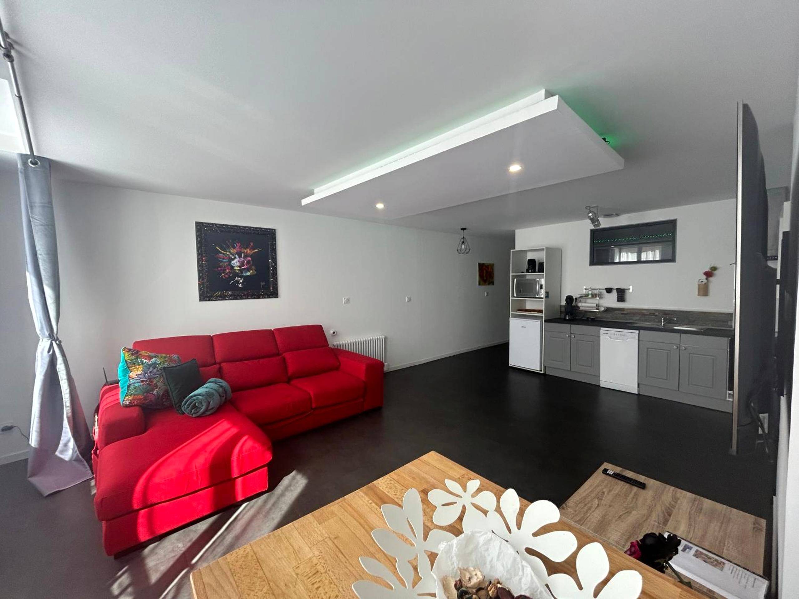 Salon avec canapé rouge et coin cuisine - Bel appart stylé avec jacuzzi
