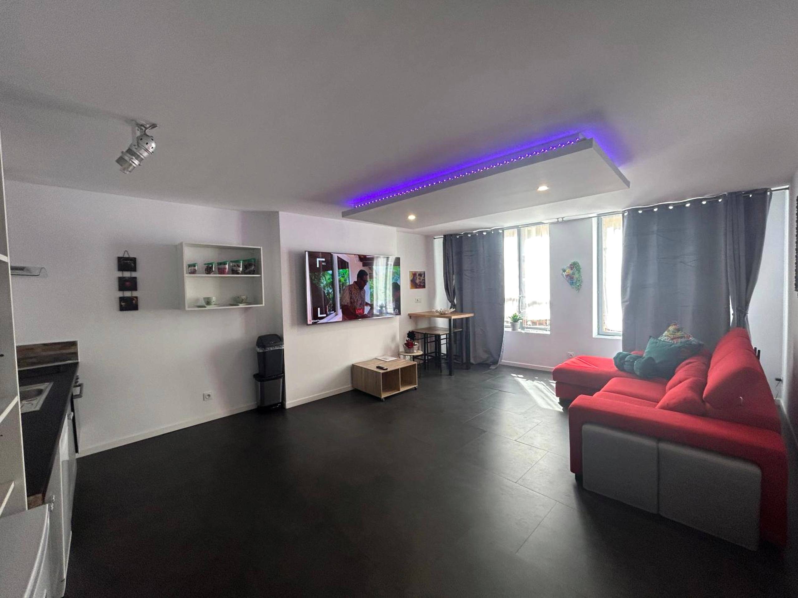 Espace de vie avec TV et plafond lumineux bleu - Bel appart stylé avec jacuzzi