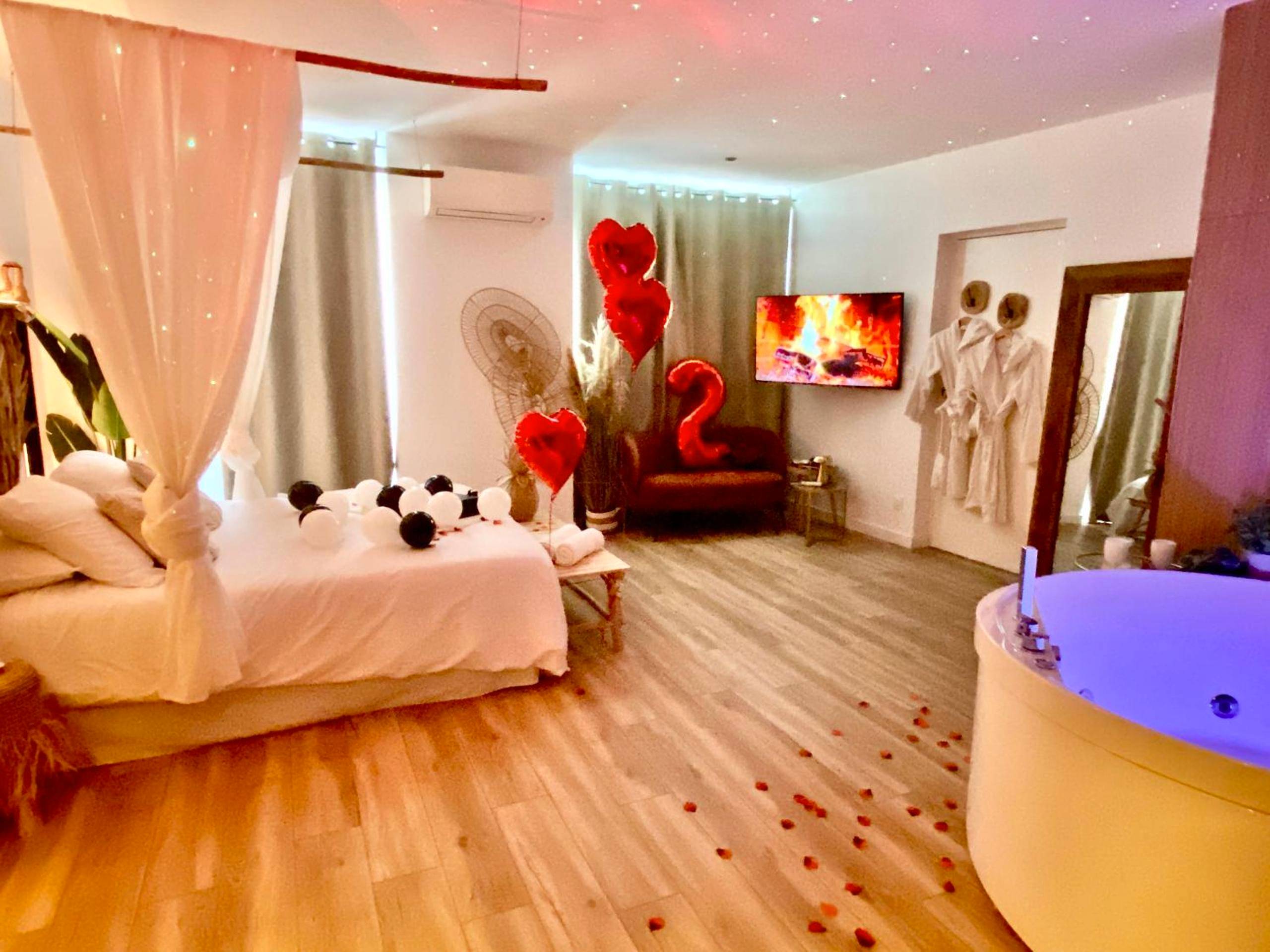 Vue d'ensemble de la suite avec jacuzzi et TV - Le Bohème Spa, loveroom à Sète