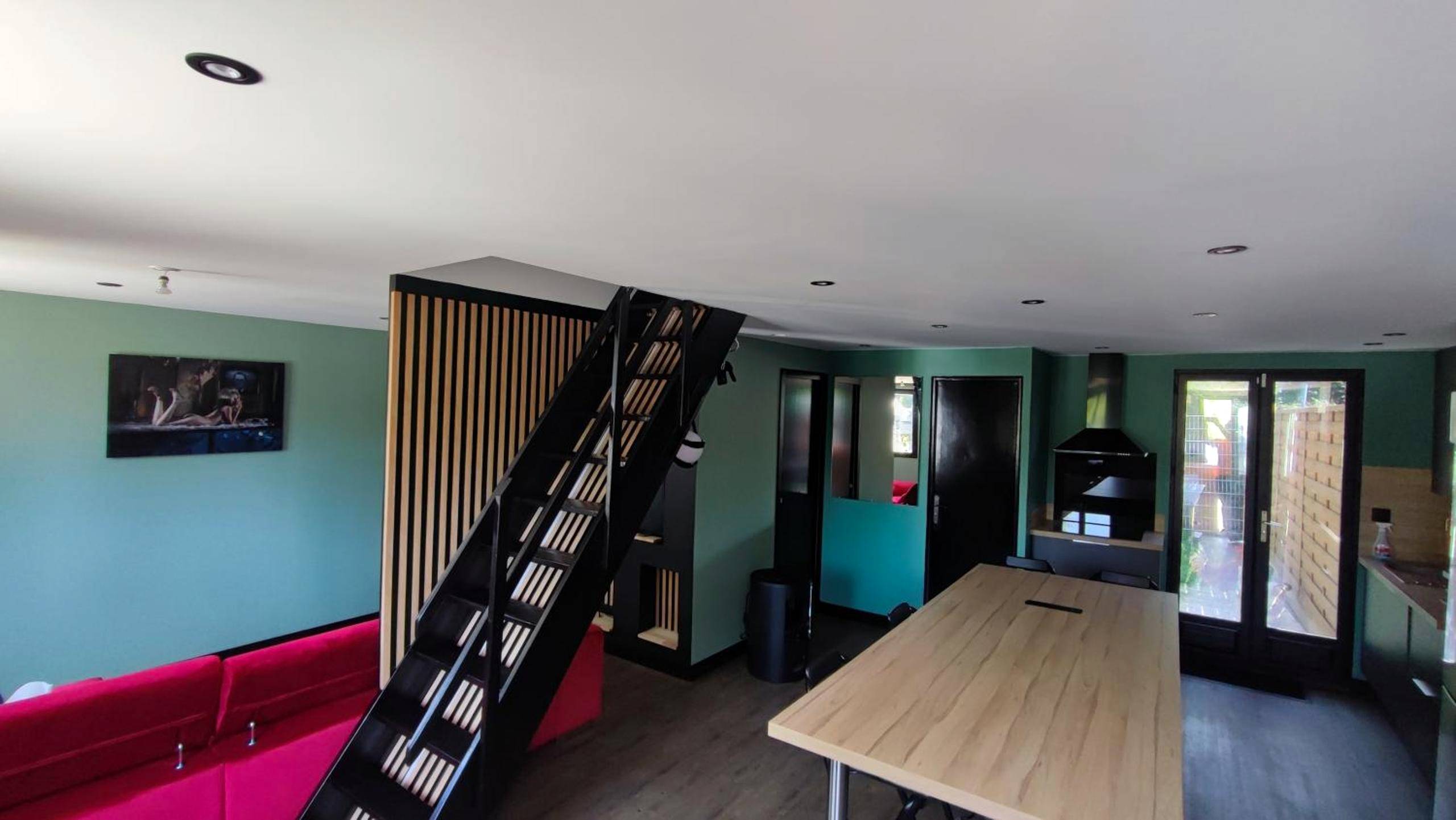 Espace de vie avec escalier noir et table en bois - Deauville Bonny and clyde room