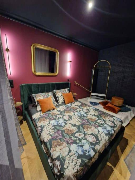 Lit double avec parure fleurie et mur pourpre - Le Boudoir D'Olympe Appartement érotico - romantique