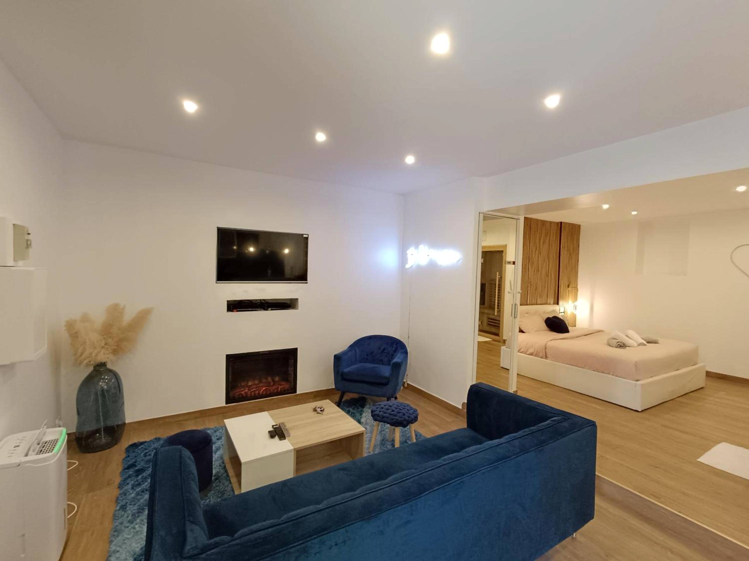 Salon avec canapé bleu et vue sur la chambre - Bulle Evasion