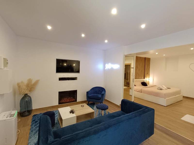 Salon avec canapé bleu et vue sur la chambre - Bulle Evasion