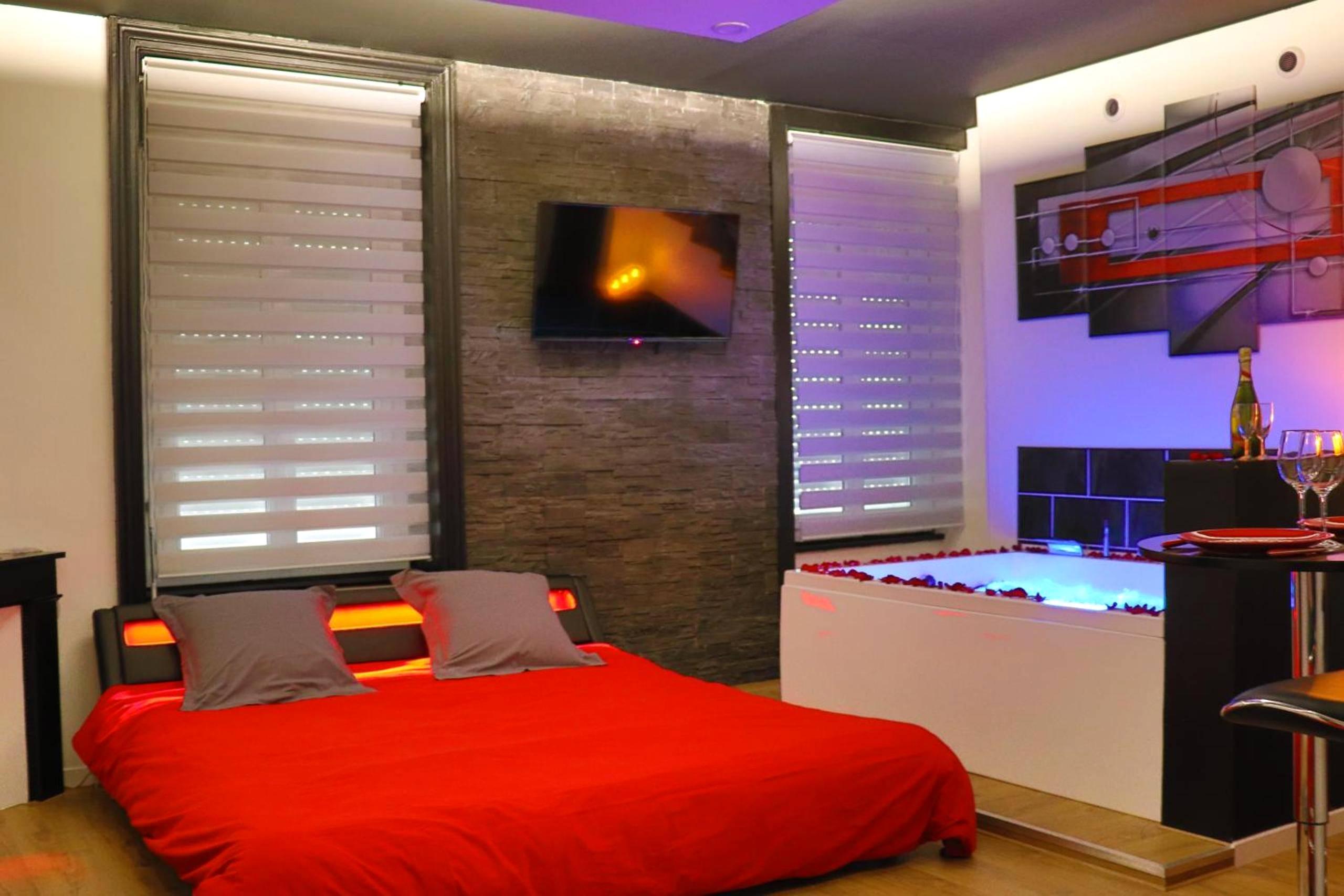 Lit double rouge et jacuzzi avec pétales - Love Room Lyon - Bulle de Spa