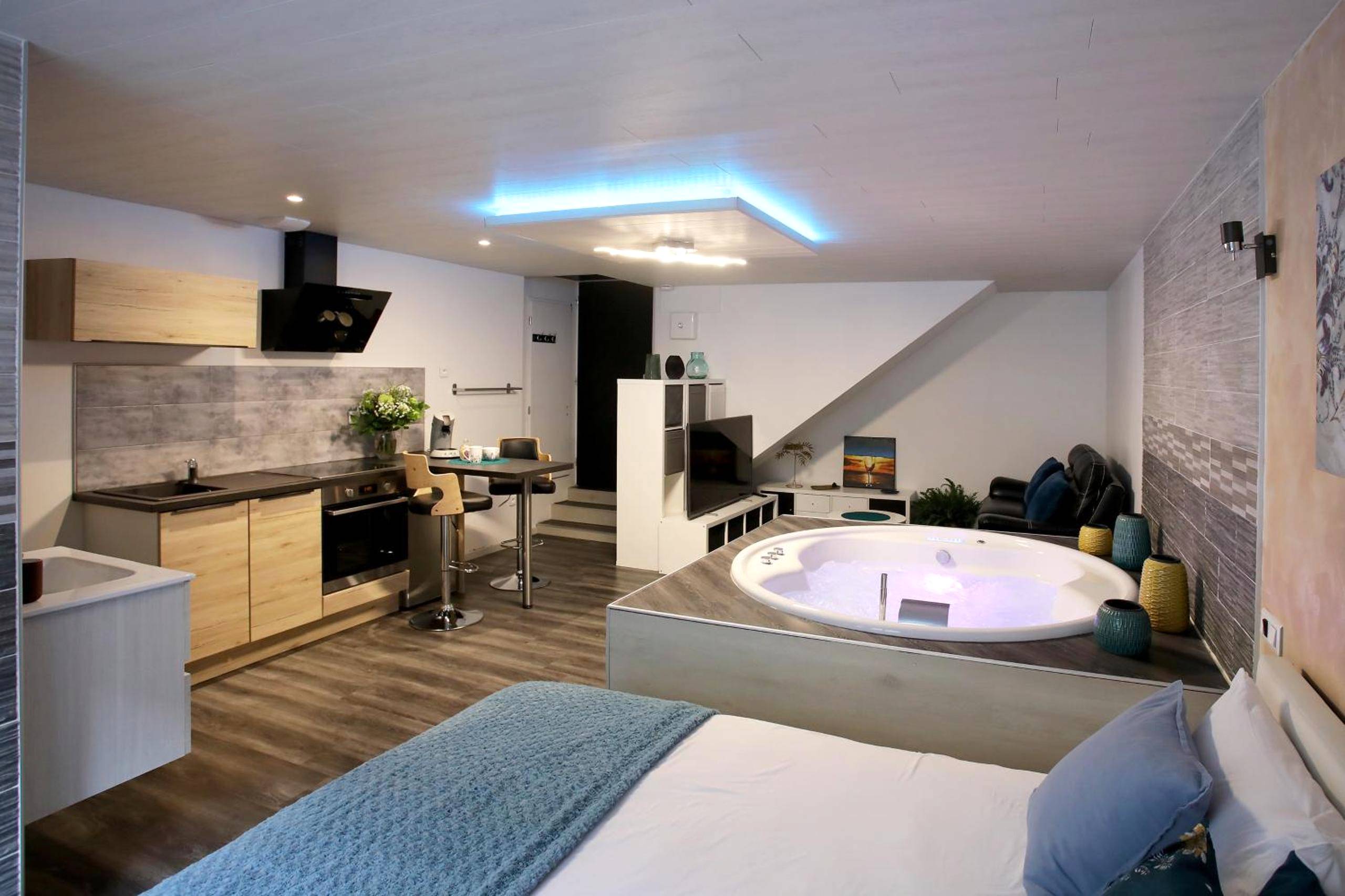 Espace de vie avec jacuzzi, cuisine et lit - Bulles Emotions