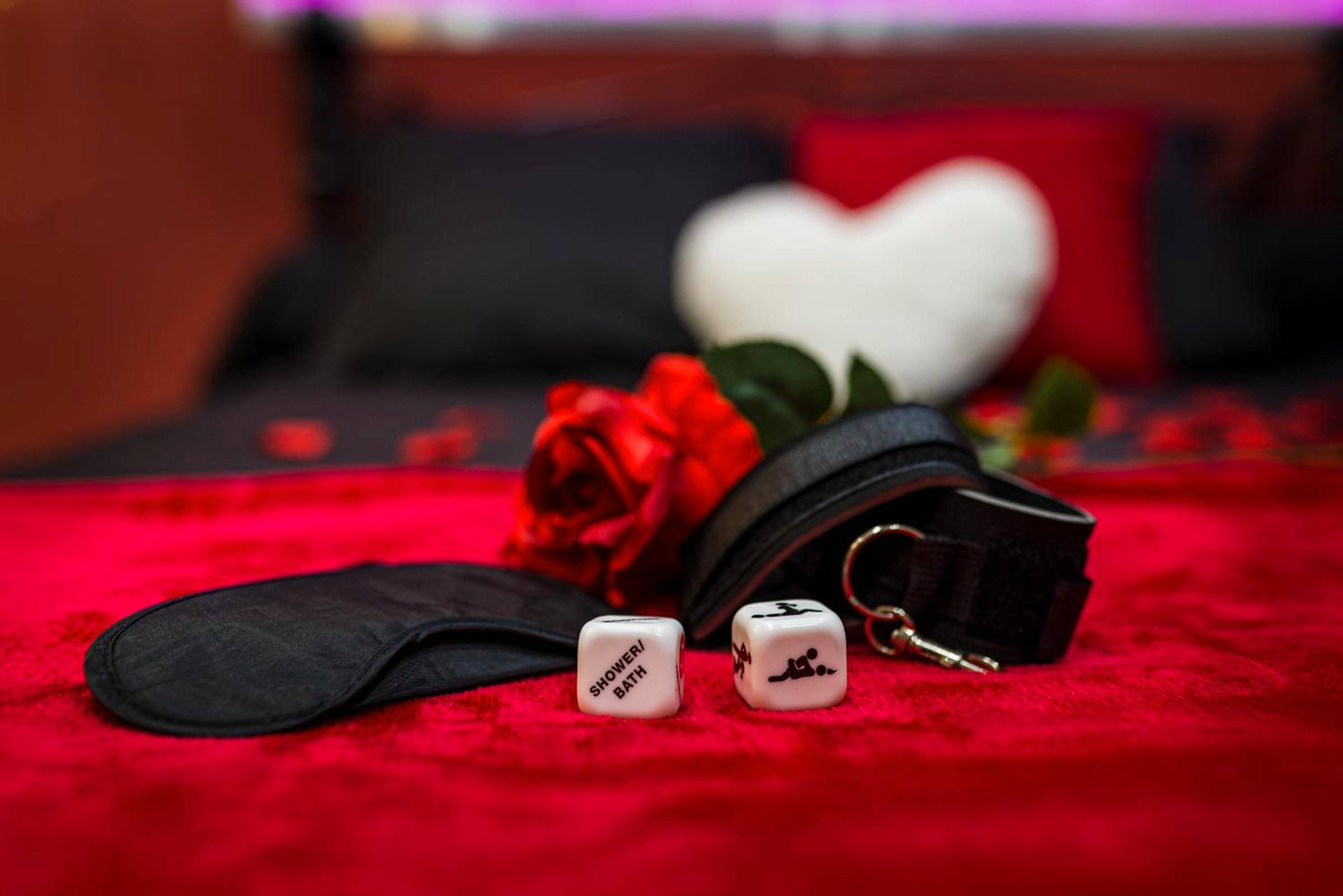 Accessoires romantiques et coquins sur lit rouge - Cachette Secrète & SPA