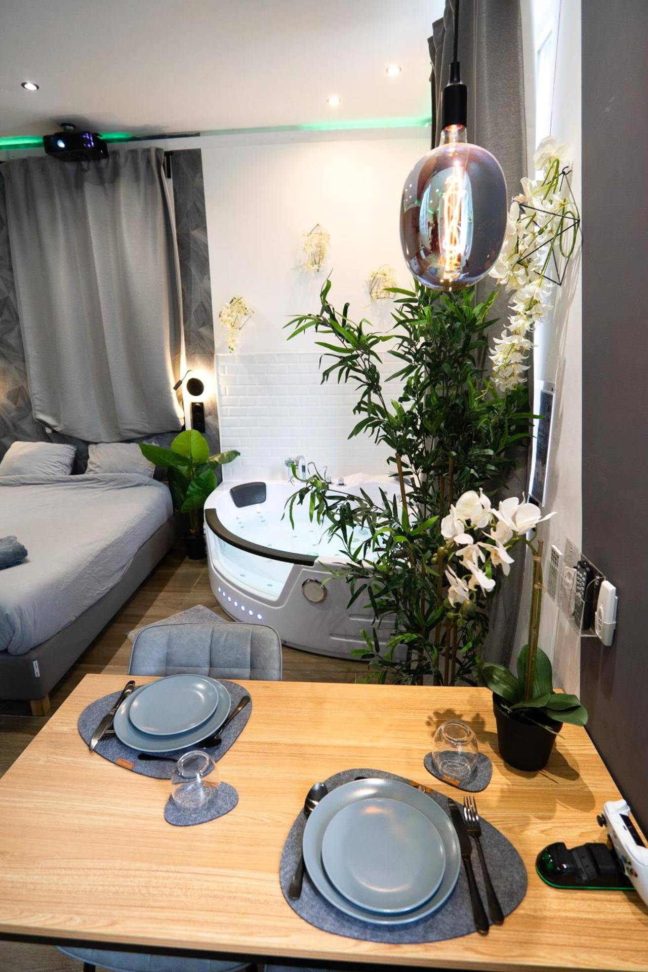 Table dressée pour deux et jacuzzi privatif - Capsule color deluxe Balnéo I écran home cinéma I console de jeux