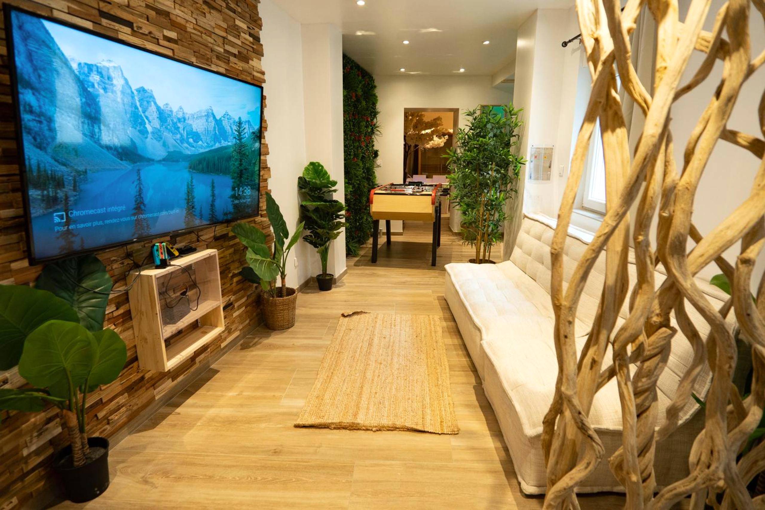 Salon avec grand écran et canapé blanc - Capsule Thailande I Sauna I Balnéo I Console I jeux en bois I Cinéma I cour...