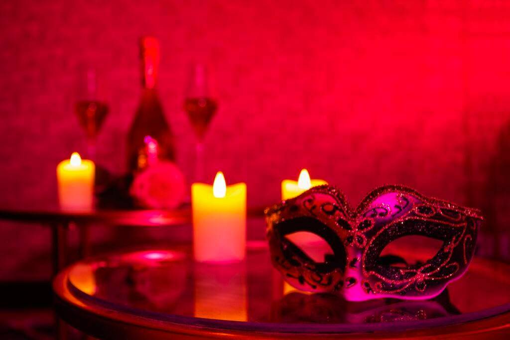 Masque vénitien et bougies sous lumière rouge - Le Carré Rose - Love Room proche de Rennes