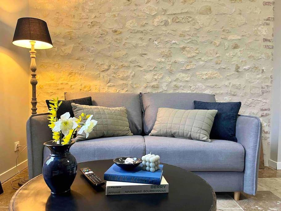 Salon avec canapé gris et mur en pierres - Maison balnéo centre - ville @casaberruyere