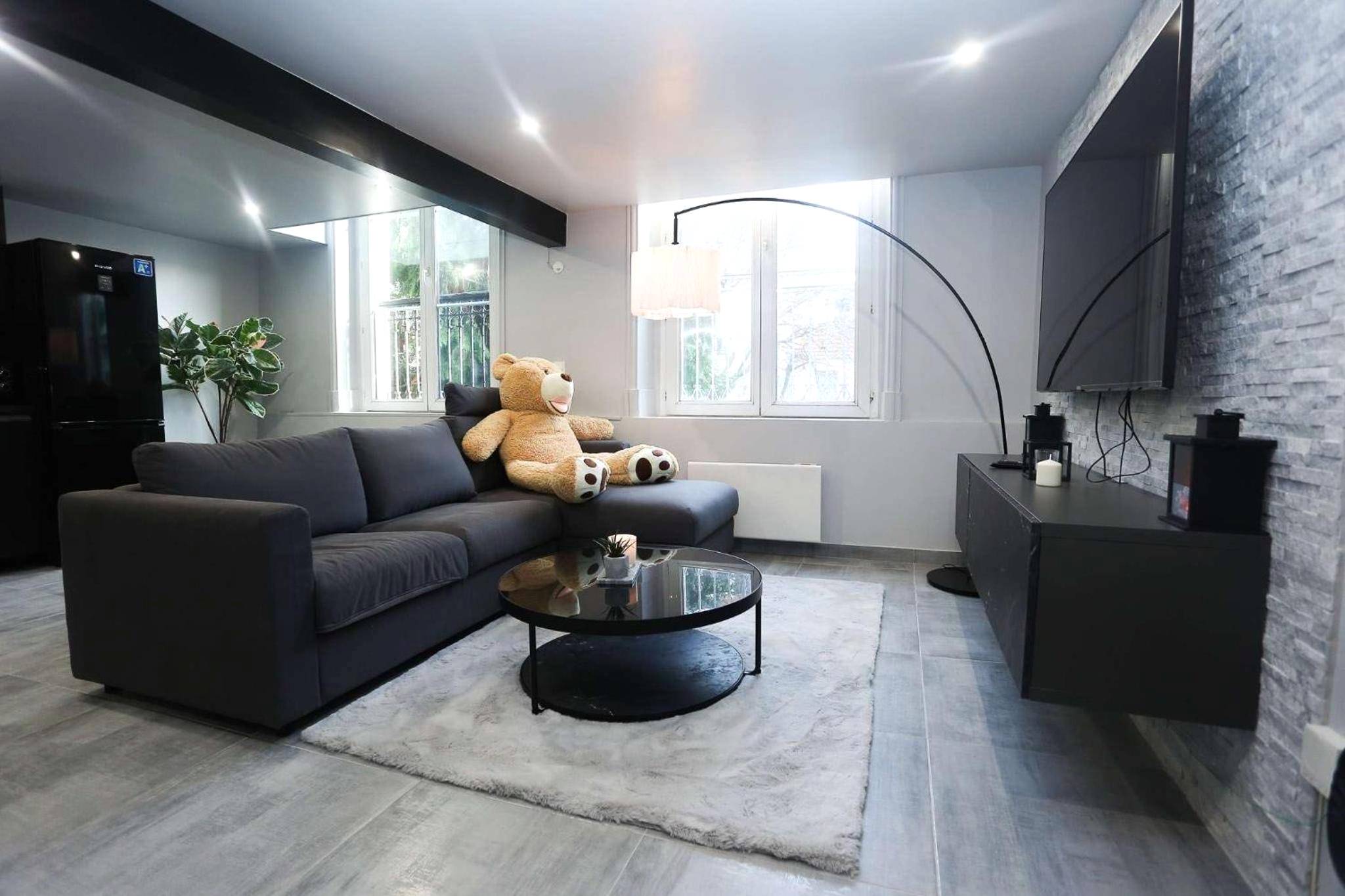 Salon avec canapé d'angle et grand ours en peluche - CasaLova