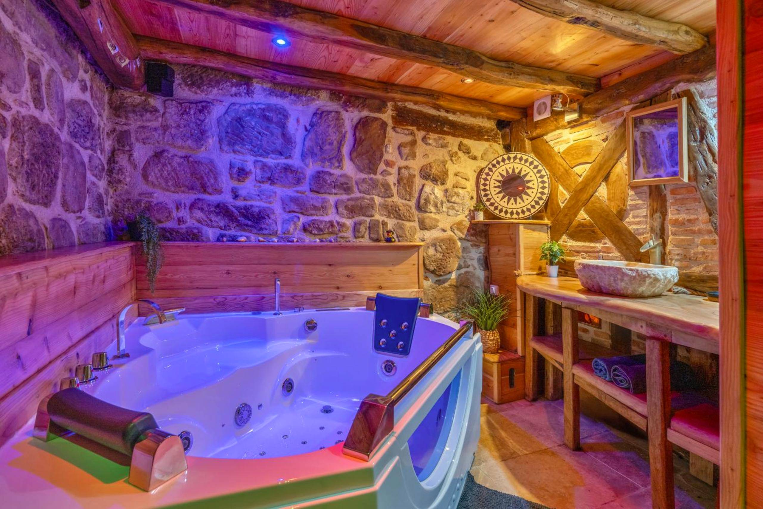 Baignoire balnéo sous plafond en bois et pierres - Love Room Figeac - Cassiopée