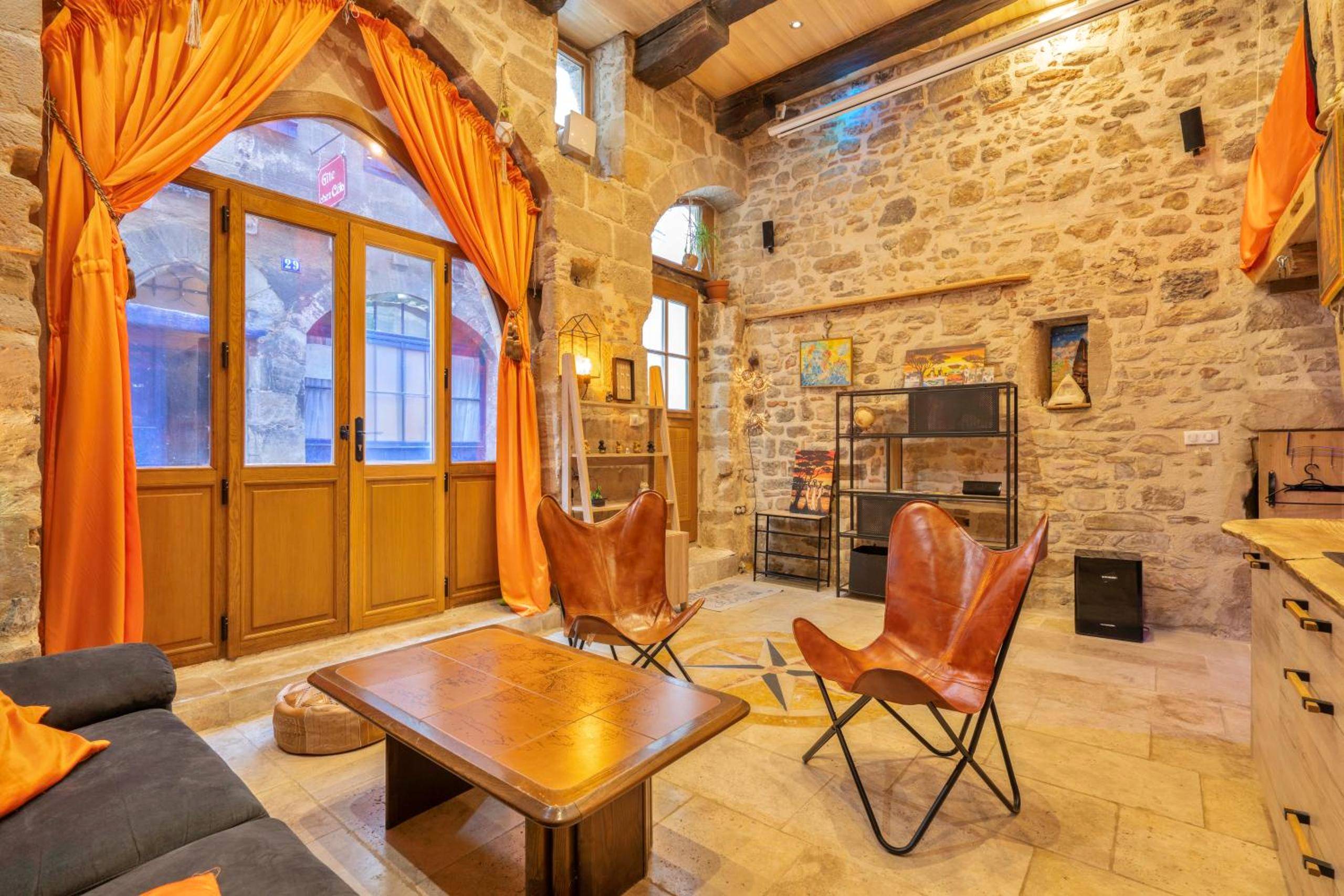 Salon avec fauteuils en cuir et rideaux orange - Cassiopée