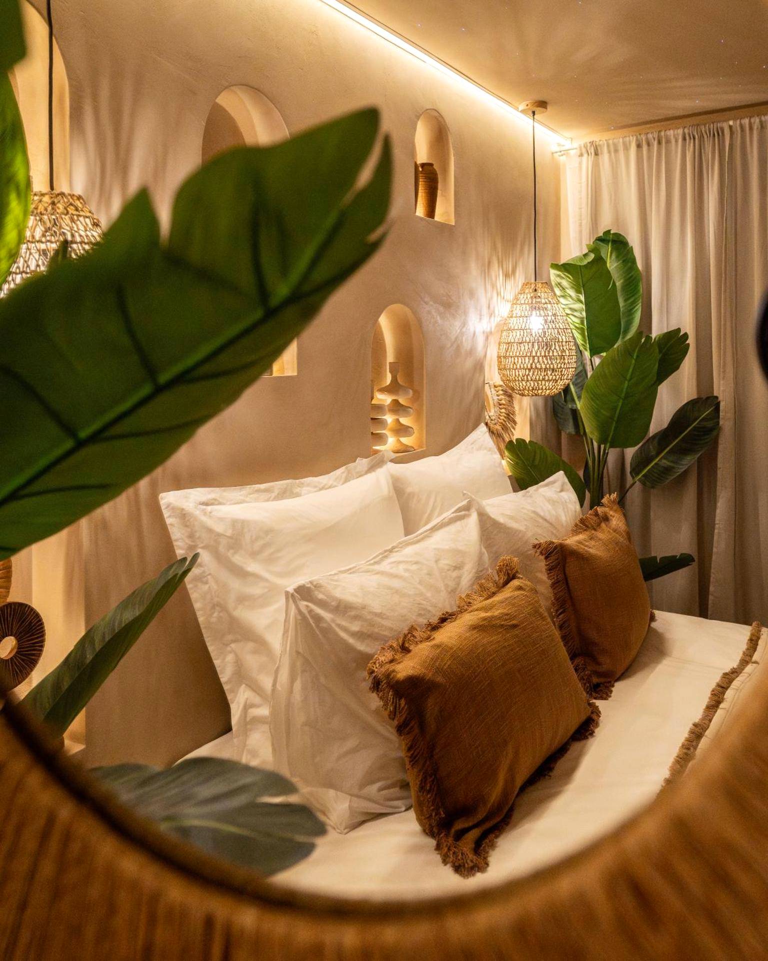 Détail du lit avec coussins et plantes vertes - Cenote Suite - Expérience sensorielle
