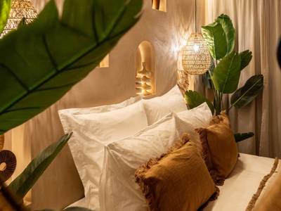 Détail du lit avec coussins et plantes vertes - Cenote Suite - Expérience sensorielle