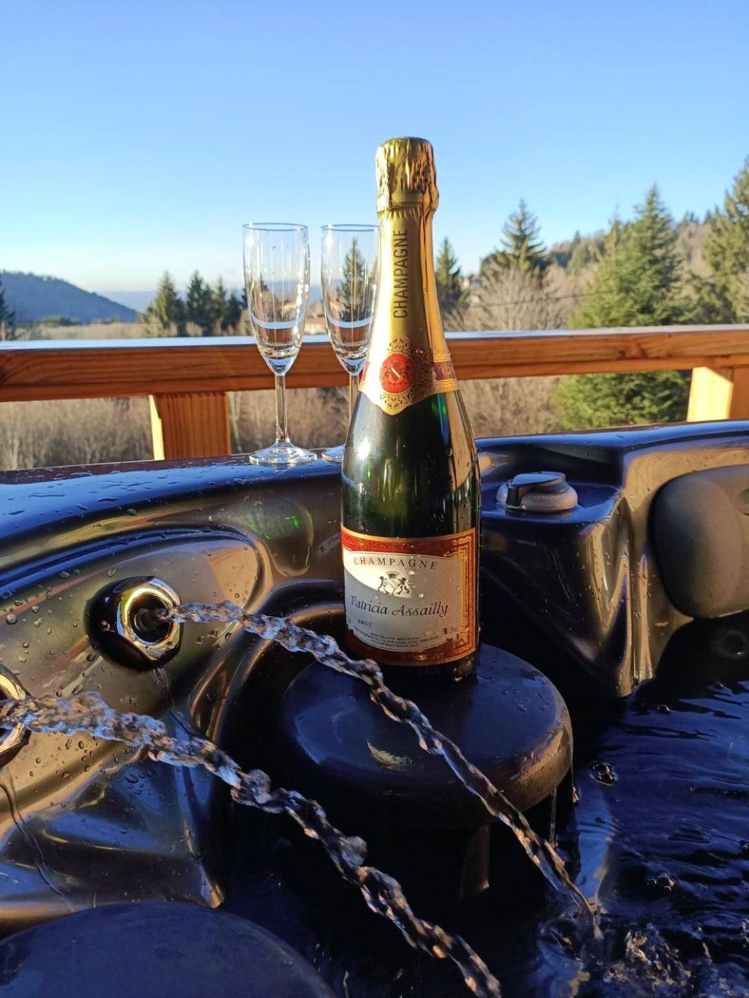 Bouteille de champagne et flûtes au bord du spa - Chalet neuf avec jacuzzi privé, vue imprenable sur Massif des Vosges